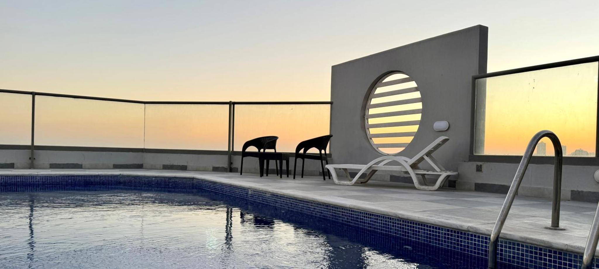 a hotel swimming pool with chairs and a mirror at Al Safwa One in Al Ḩadd