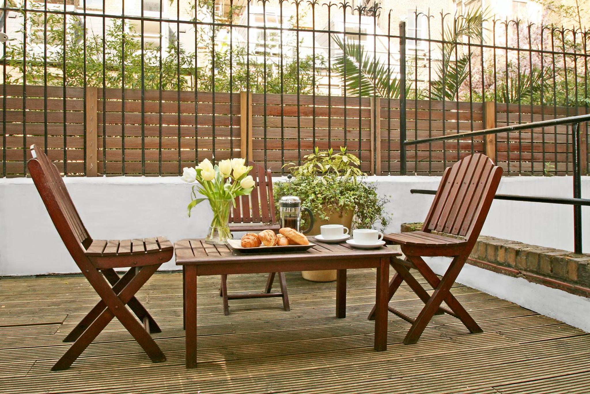 a table and two chairs with a plate of food on a patio at Collingham Serviced Apartments in London