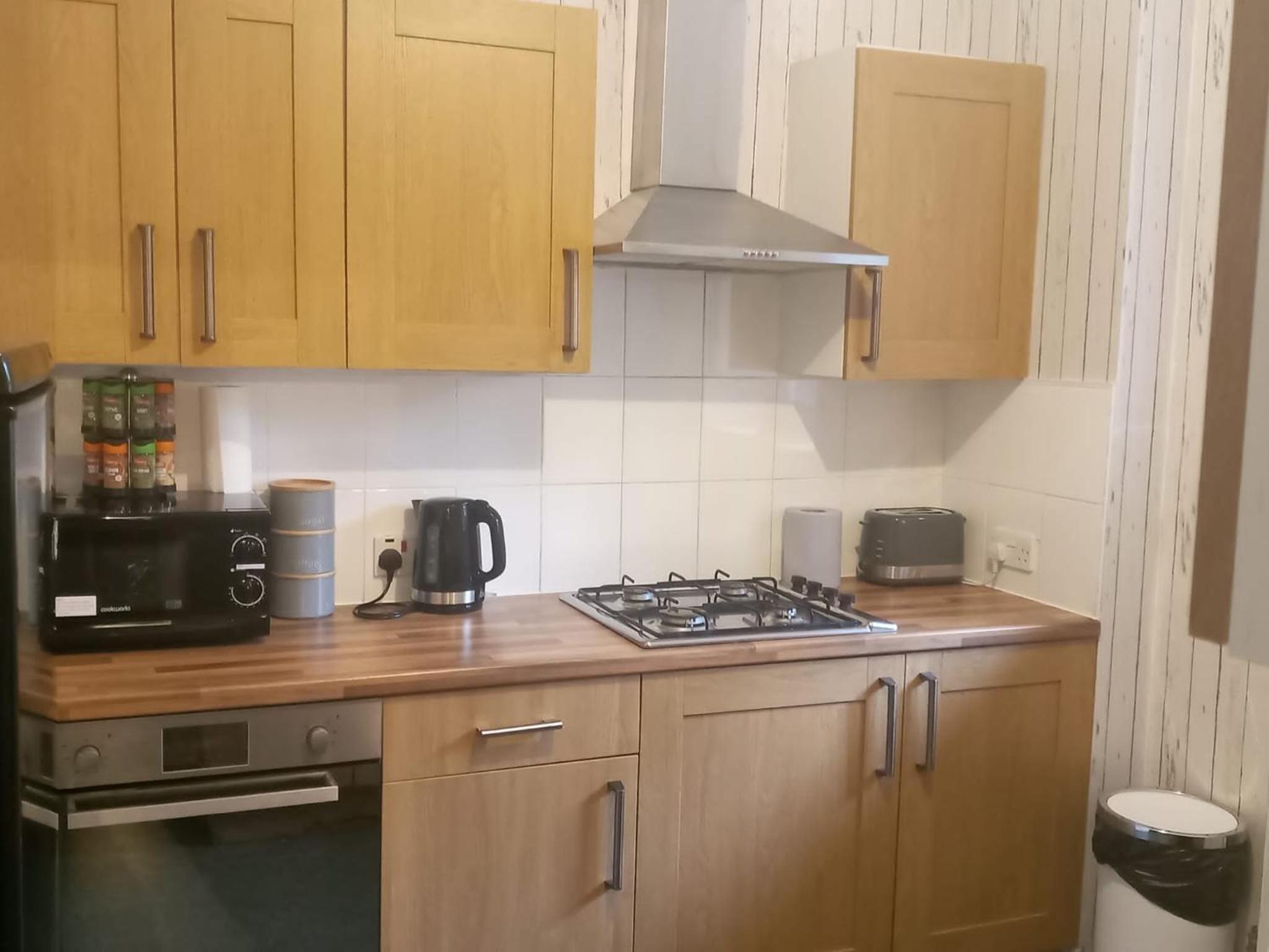 a kitchen with wooden cabinets and a stove top oven at The London Apartment in London +9 photos