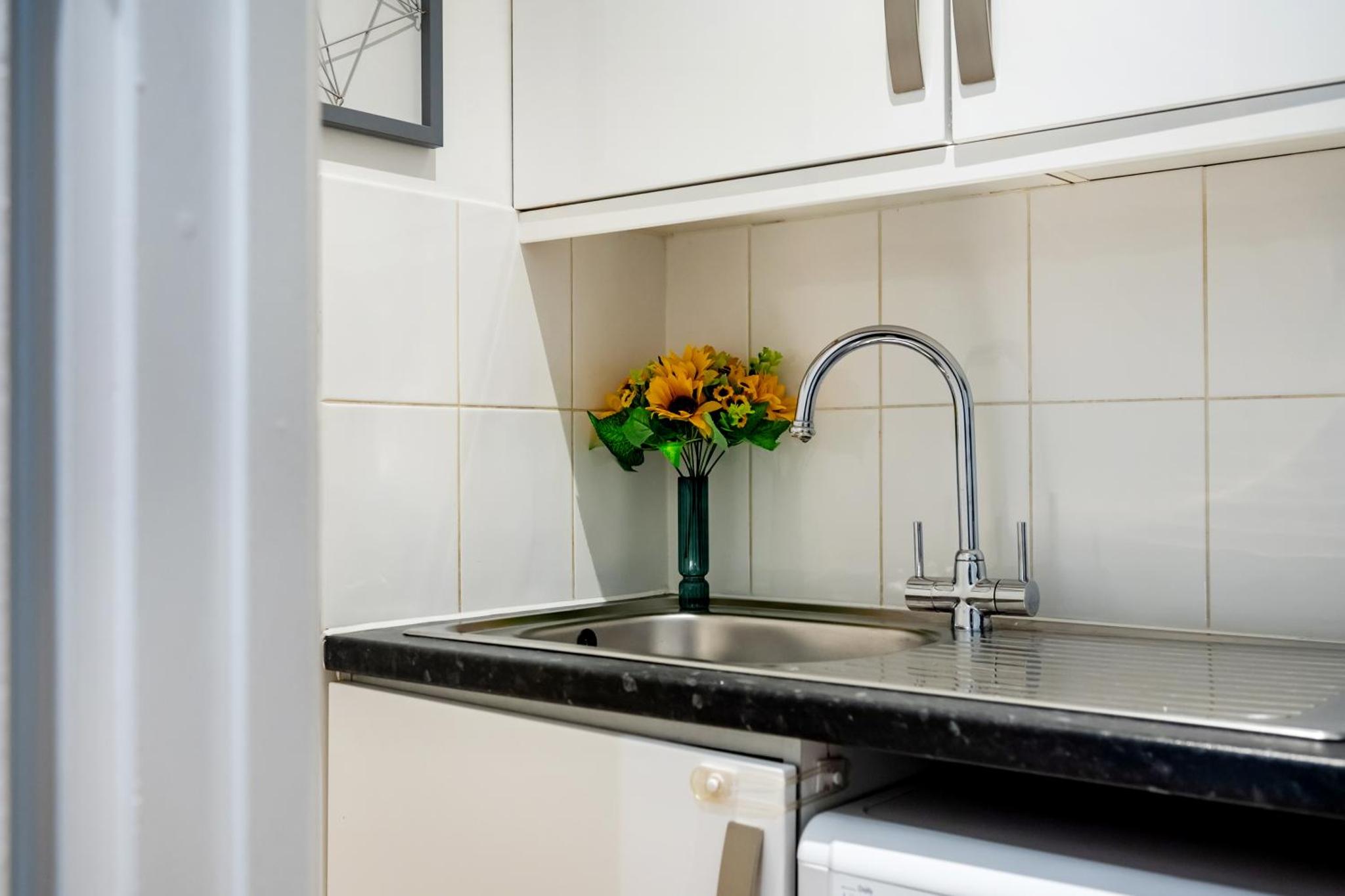 a kitchen with a sink and a vase of flowers at Welcome London - Short's Gardens in London