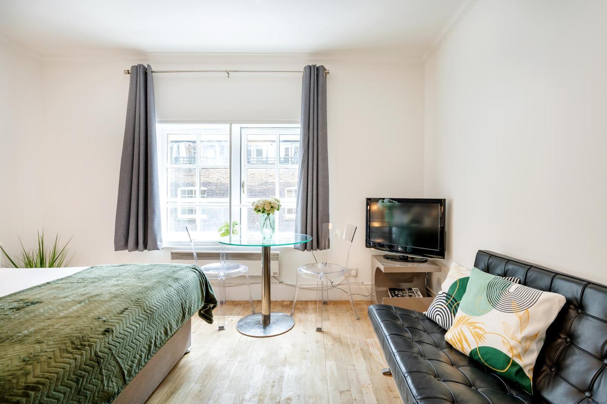 a bedroom with a bed and a table and a tv at Welcome London - Short's Gardens in London