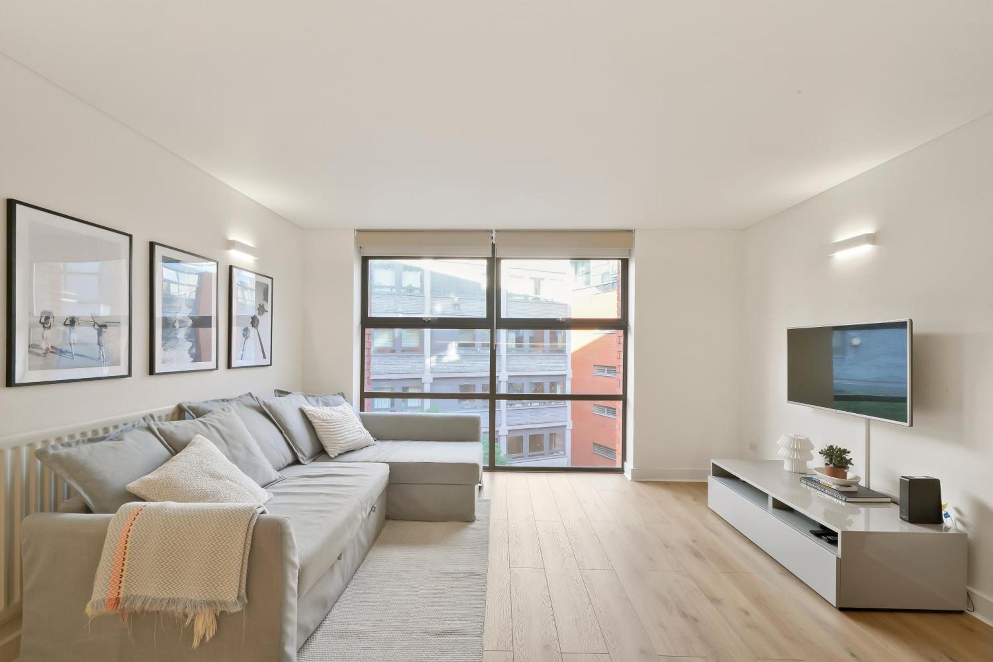 a white living room with a couch and a tv at Flat 315, 33 Birtton Street in London