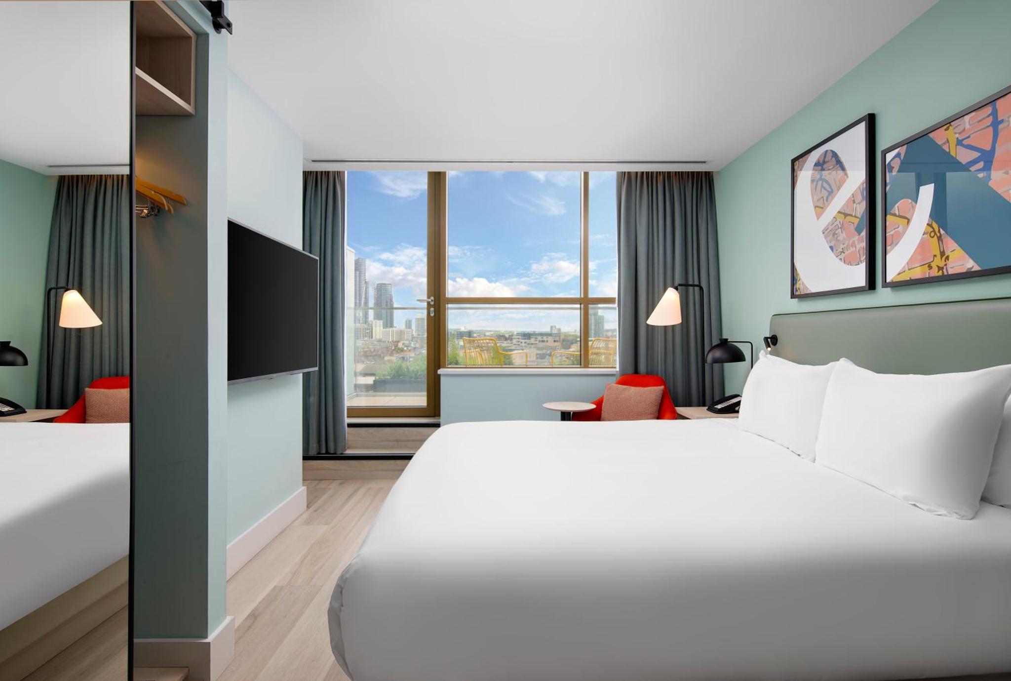 a hotel room with a large bed and a large window at Hyatt Place London City East in London