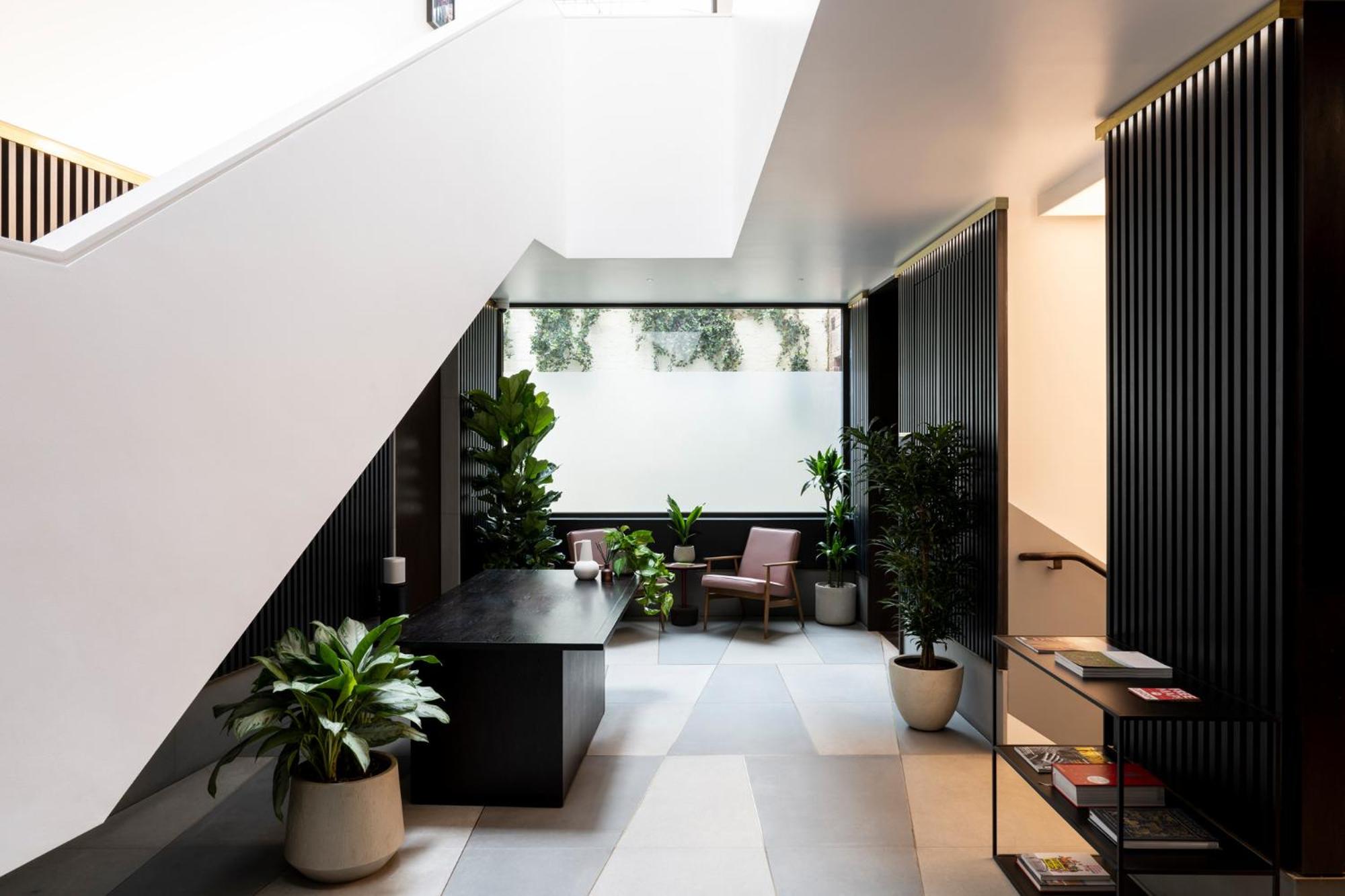 a hallway with potted plants and a staircase at The Moorgate by COVE in London