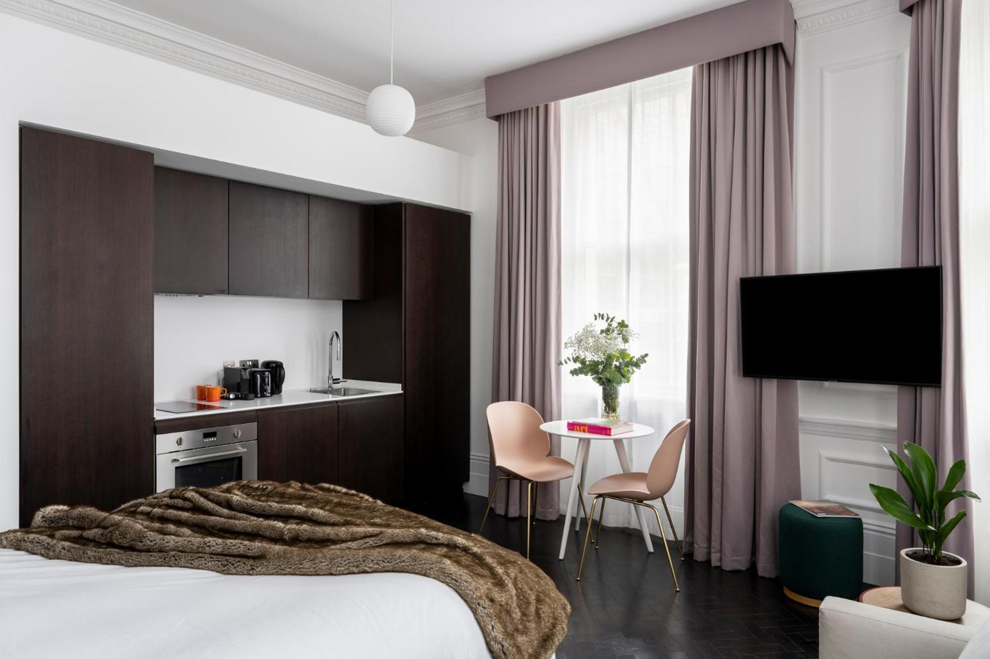 a bedroom with a bed and a table with chairs at The Moorgate by COVE in London