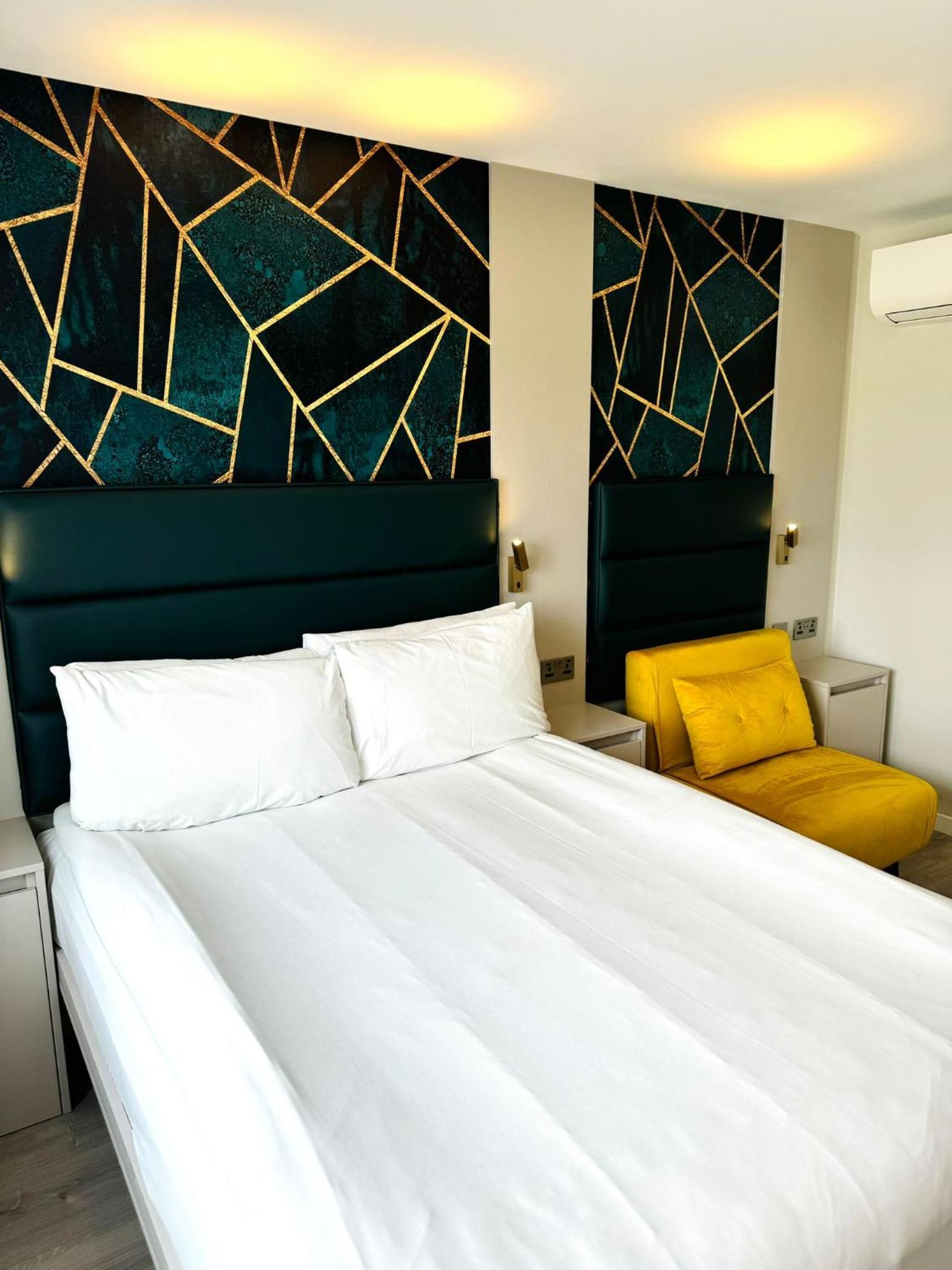 a bedroom with a white bed and a yellow chair at Victoria Studios in London