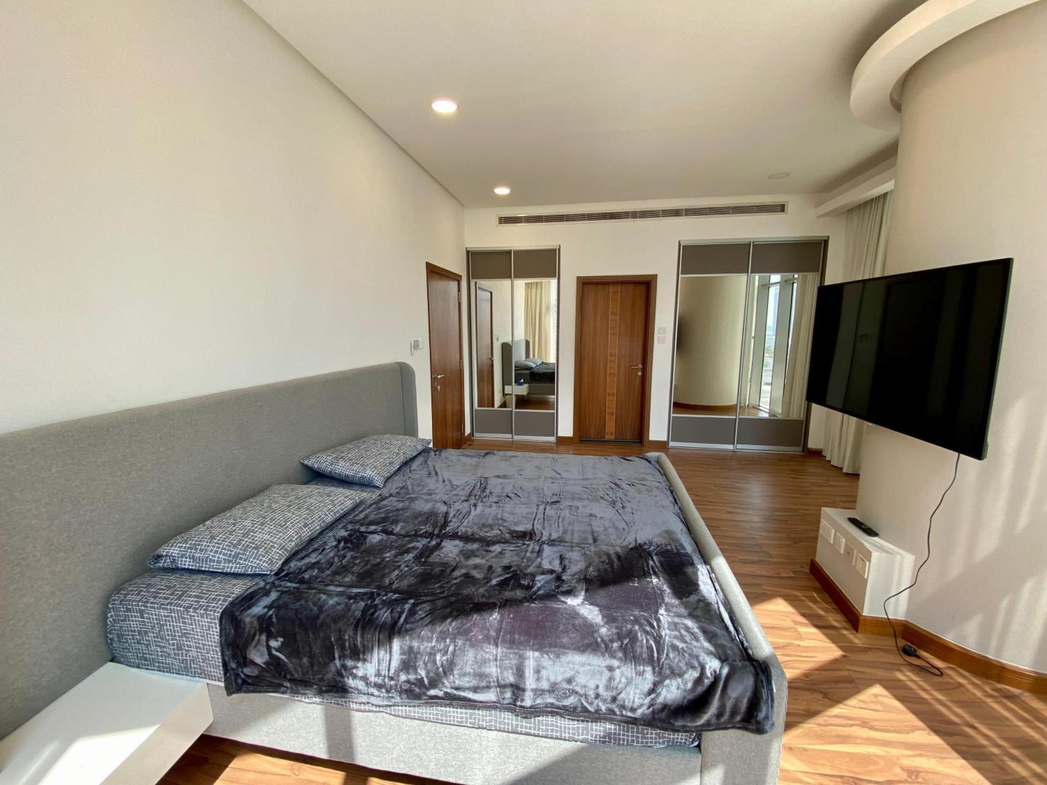 a bedroom with a bed and a flat screen tv at Seef Serenity - Sea & City Views in Manama