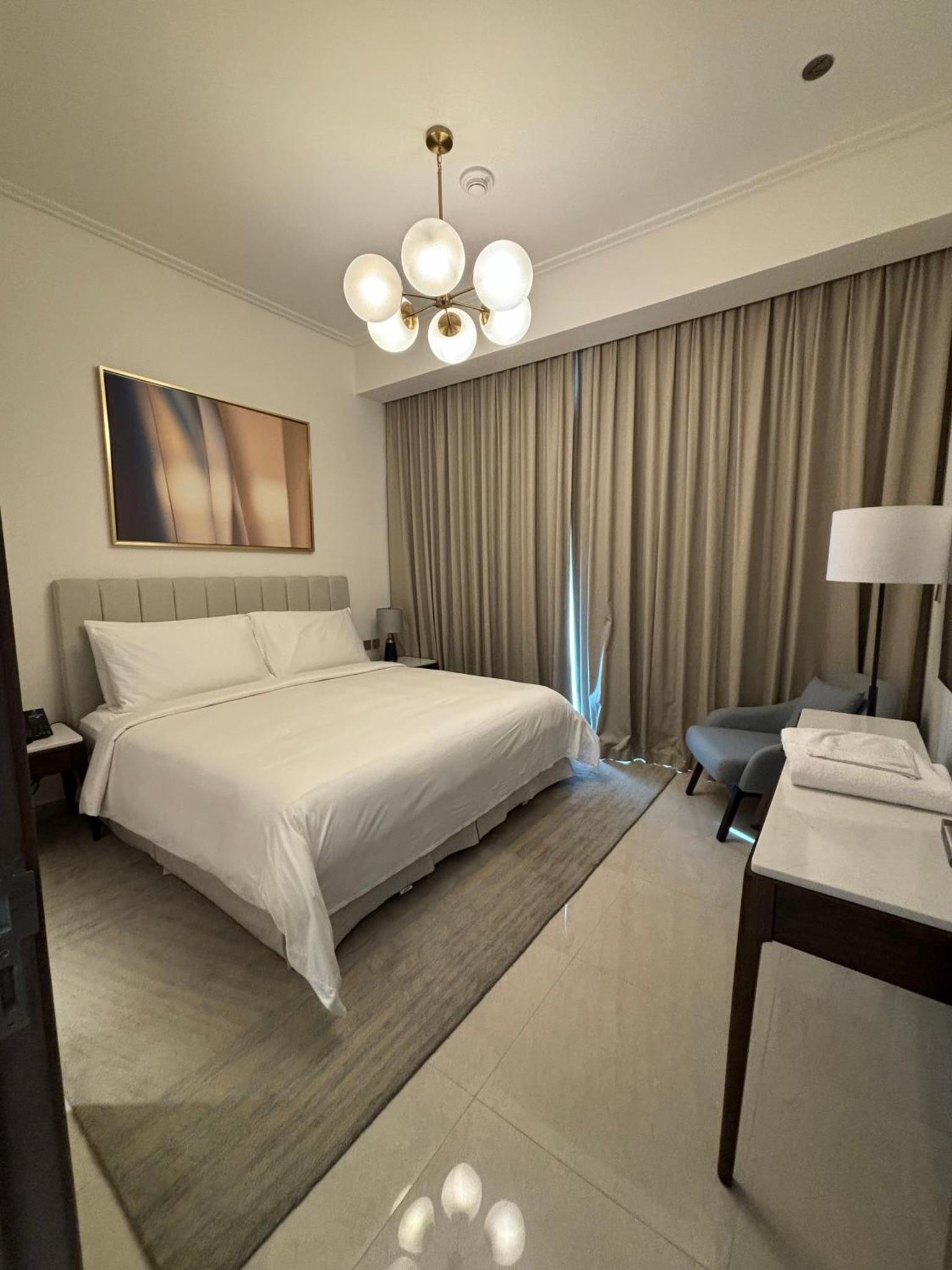 a bedroom with a large white bed and a chandelier at Address Beach Resort Residence - Bahrain in Rayyā