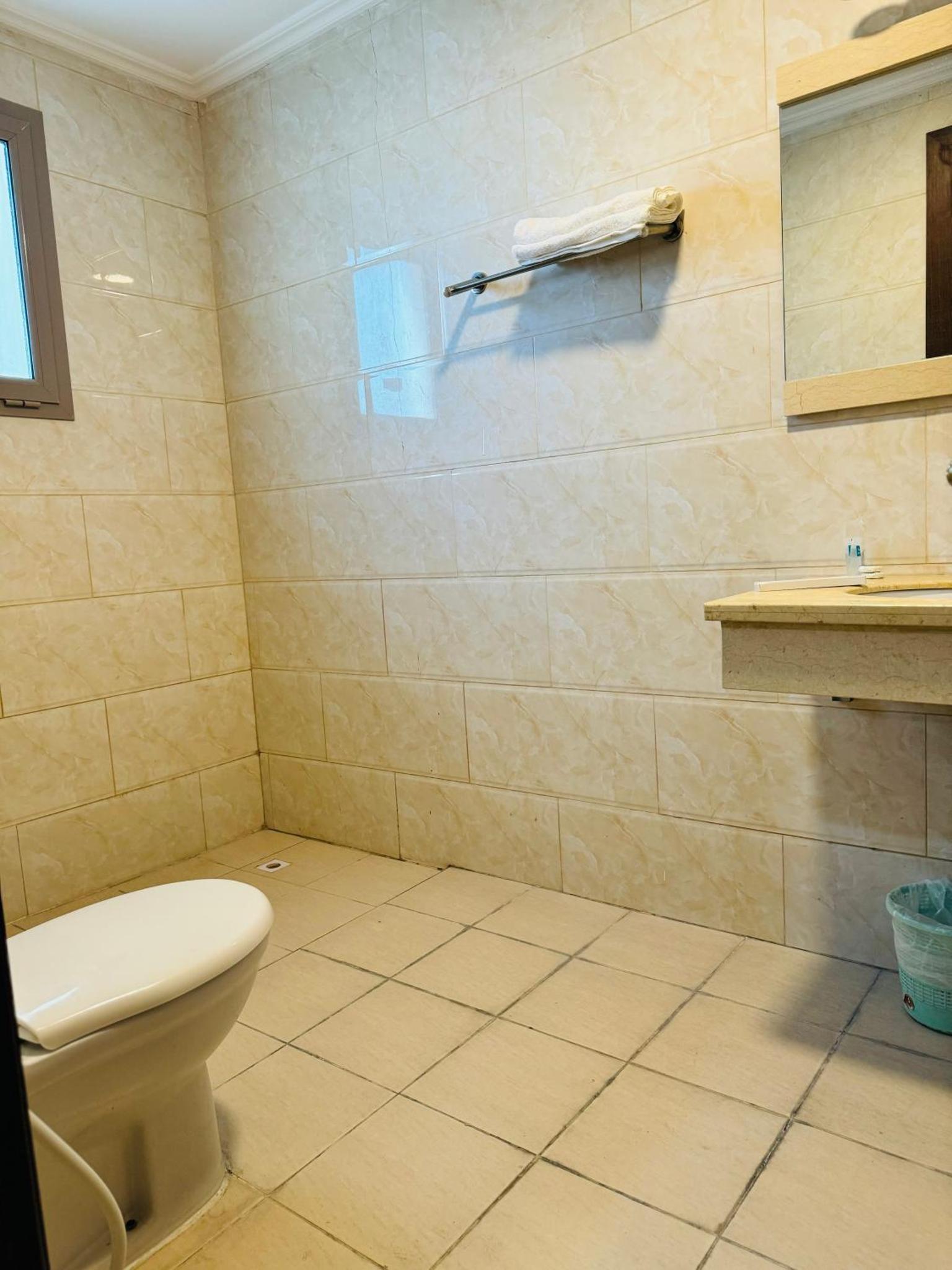 a bathroom with a toilet and a tiled wall at Al Hayat Suites Apartment in Manama +35 photos