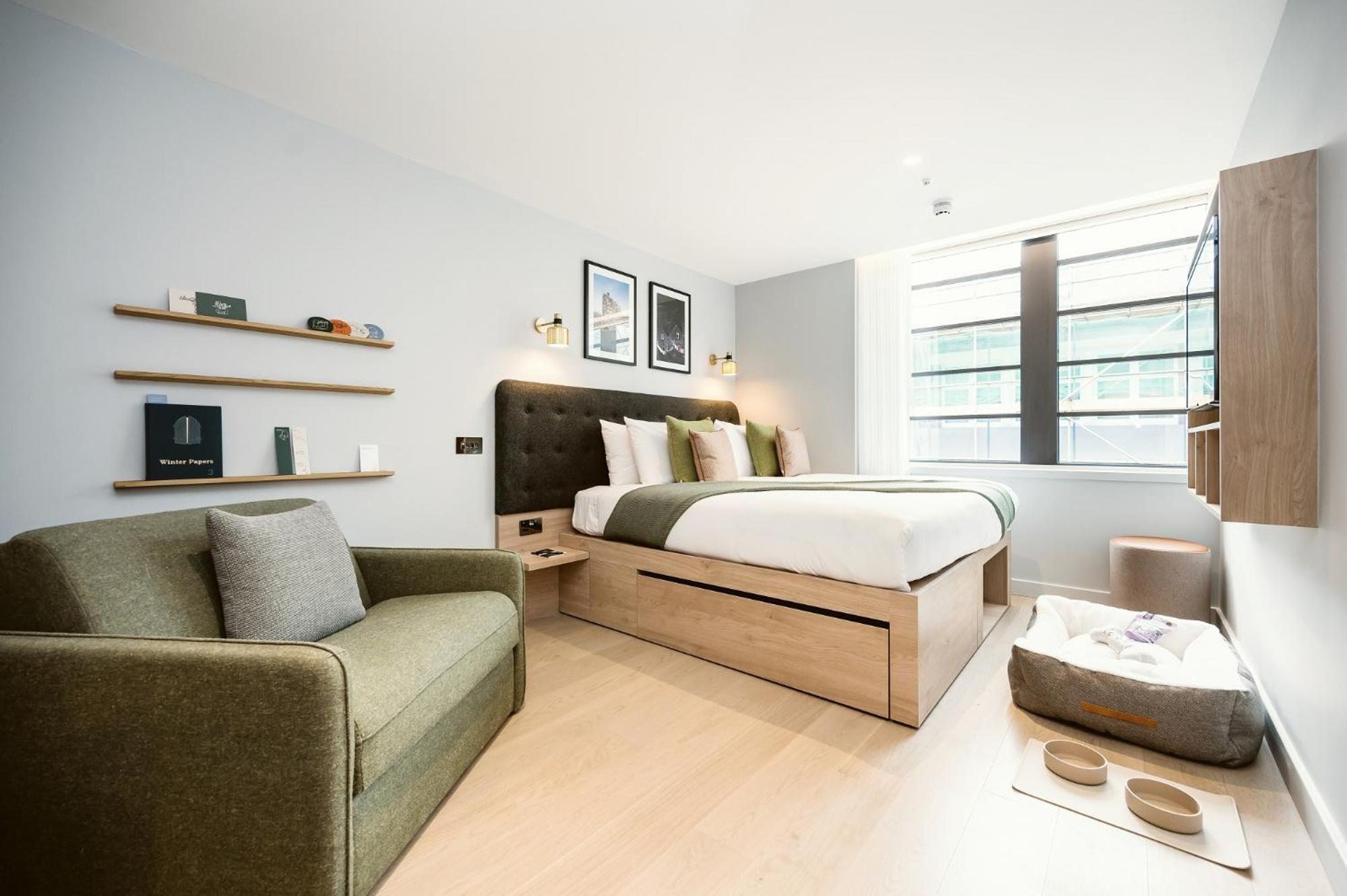 a bedroom with a bed and a couch and a chair at Wilde Aparthotels London Liverpool Street in London