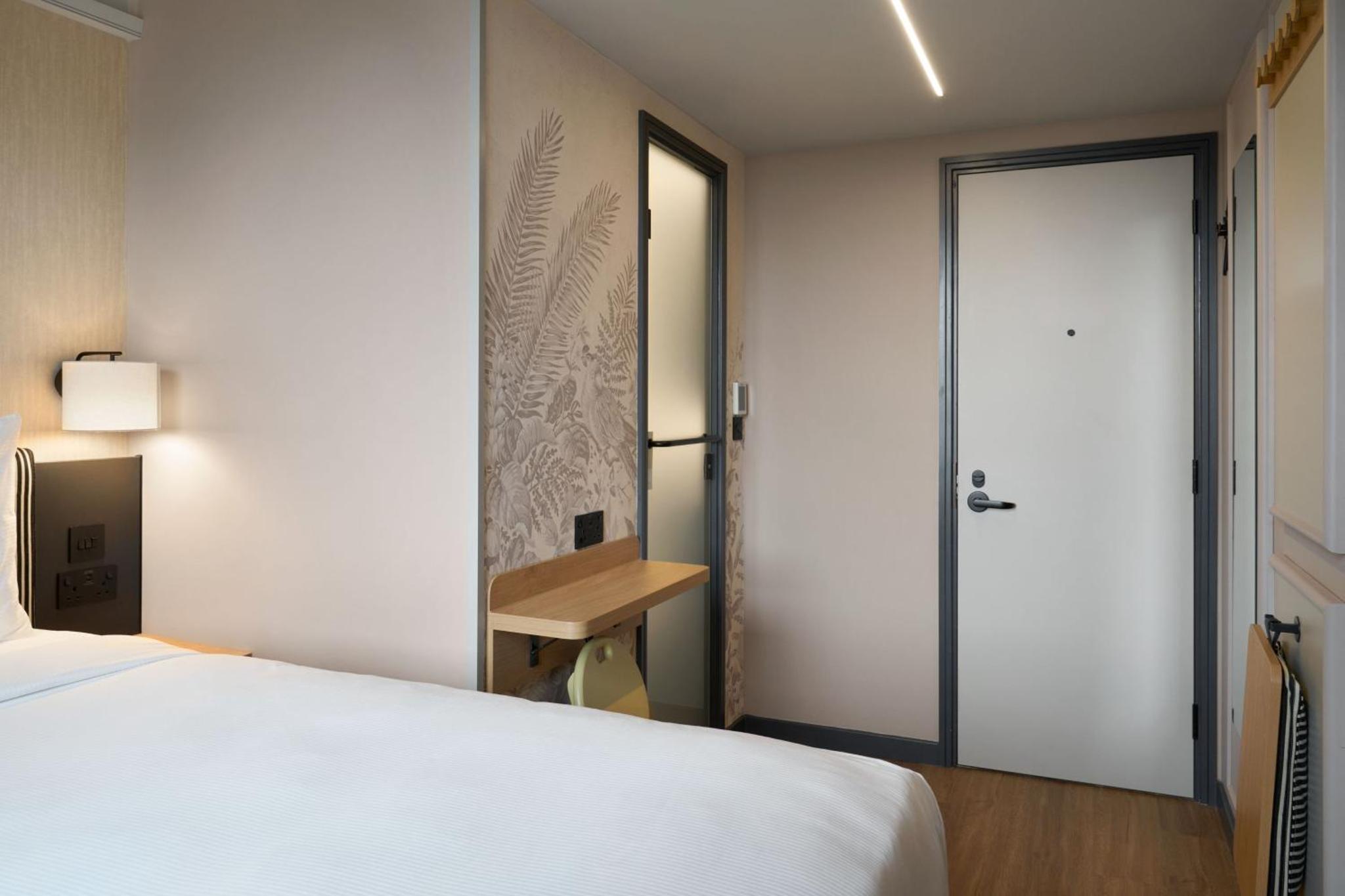 a bedroom with a white bed and a sliding door at Four Points Flex by Sheraton London Euston in London