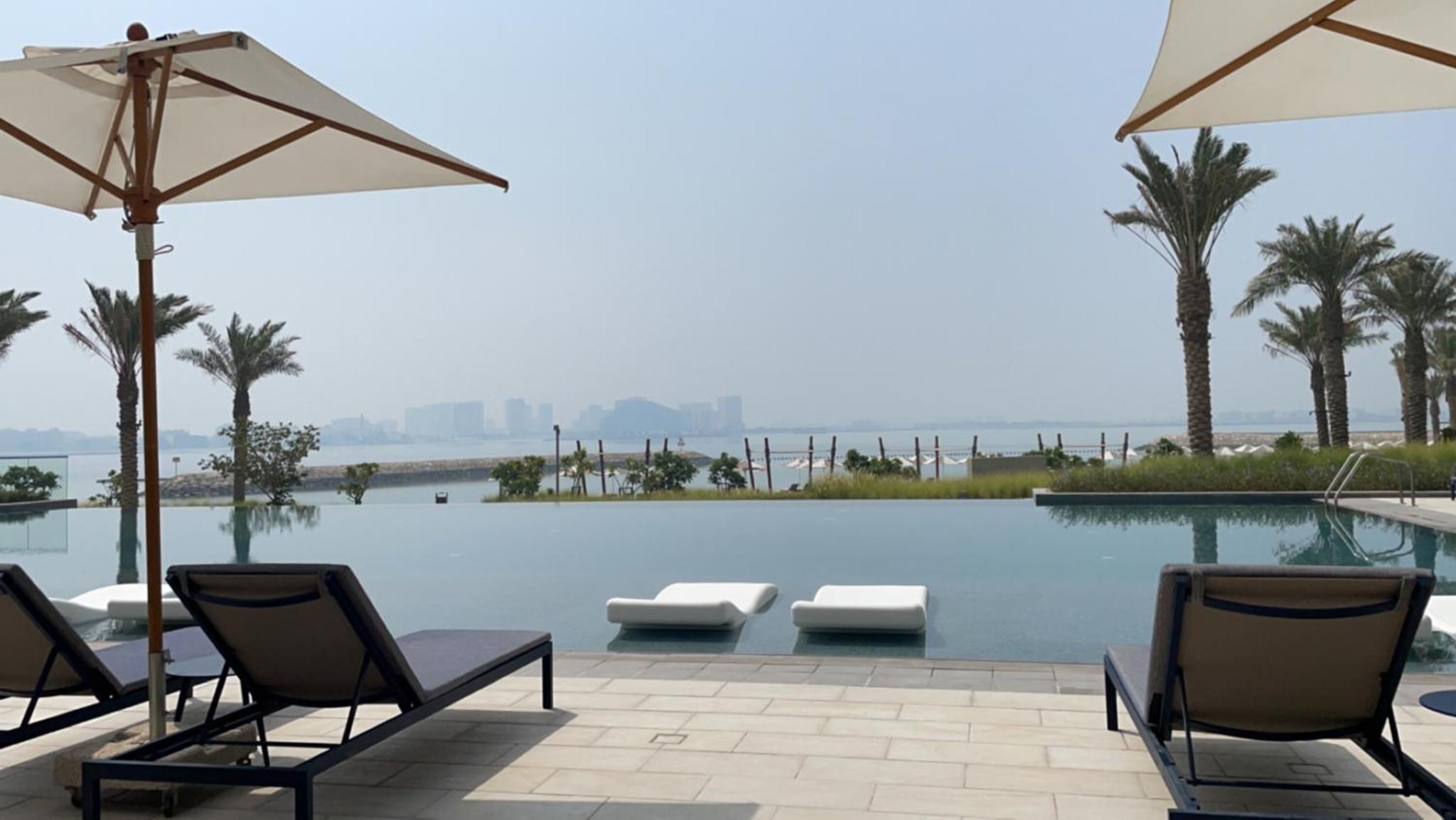 a swimming pool with chairs and umbrellas at Address Beach Resort Residence - Bahrain in Rayyā +9 photos