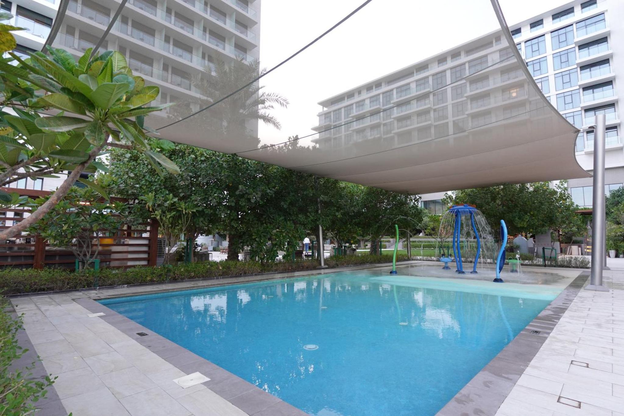 a large swimming pool with a slide in a building at Address Residence Bahrain in Rayyā