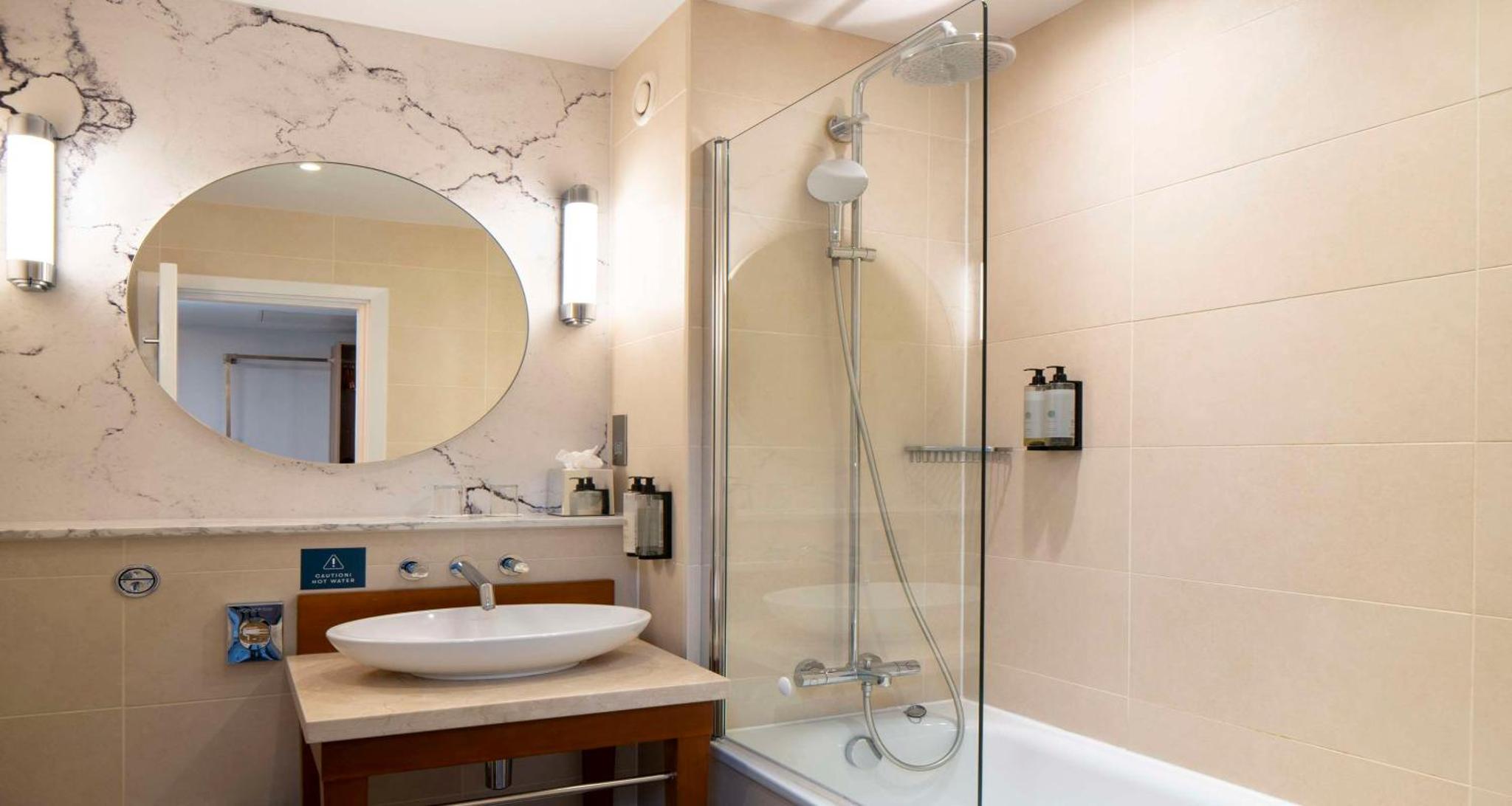 a bathroom with a sink and a shower with a mirror at London Chigwell Prince Regent Hotel, BW Signature Collection in London