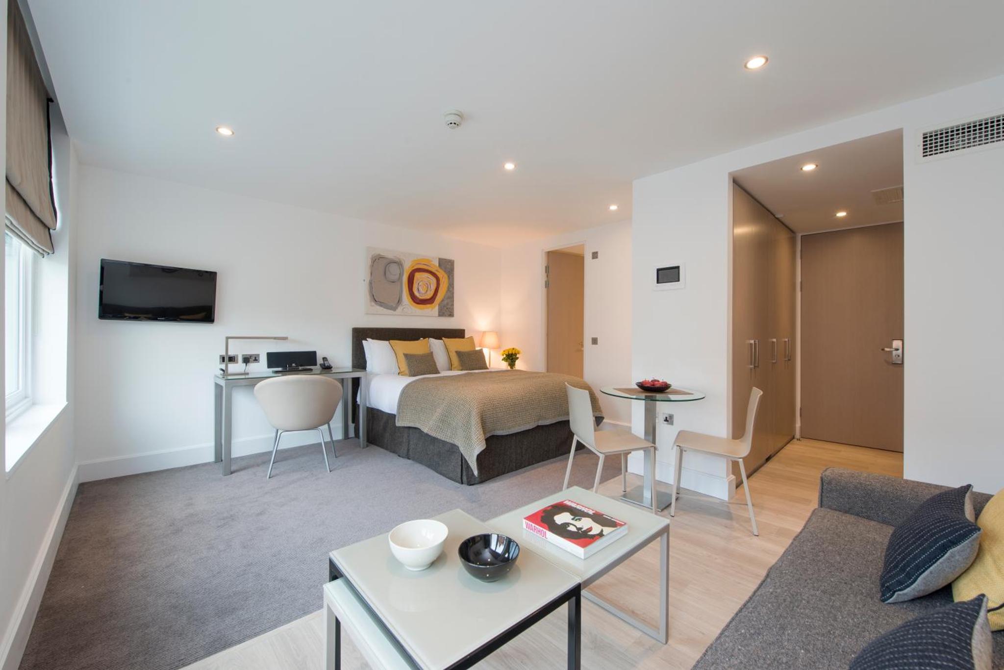 a bedroom and living room with a bed and a table at The Rosebery by Supercity Aparthotels in London