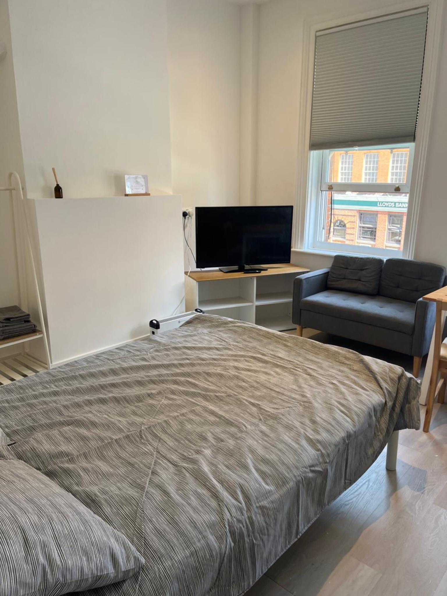 a bedroom with a bed and a couch and a television at Camden BNB in London +5 photos