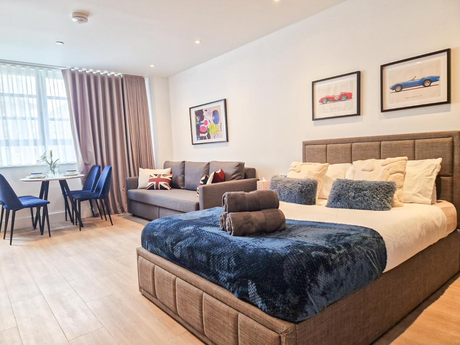 a bedroom with a large bed and a living room at 3-Bedroom with Balcony and Studio Apartments in St Johns Wood near Marylebone & Regents Park by NourNest Apartments in London