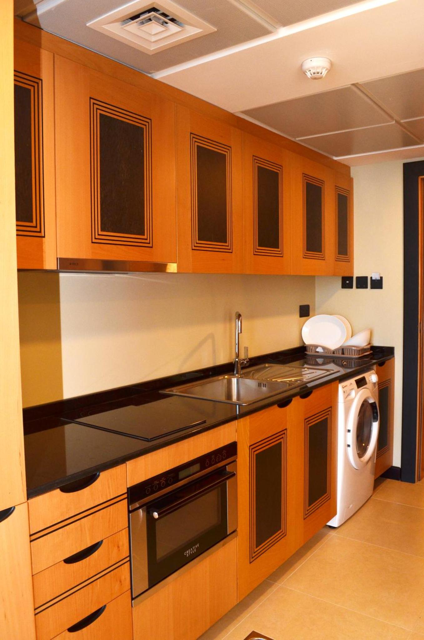 a kitchen with wooden cabinets and a sink and a dishwasher at Nooh Apartment in Al Ḩadd +33 photos