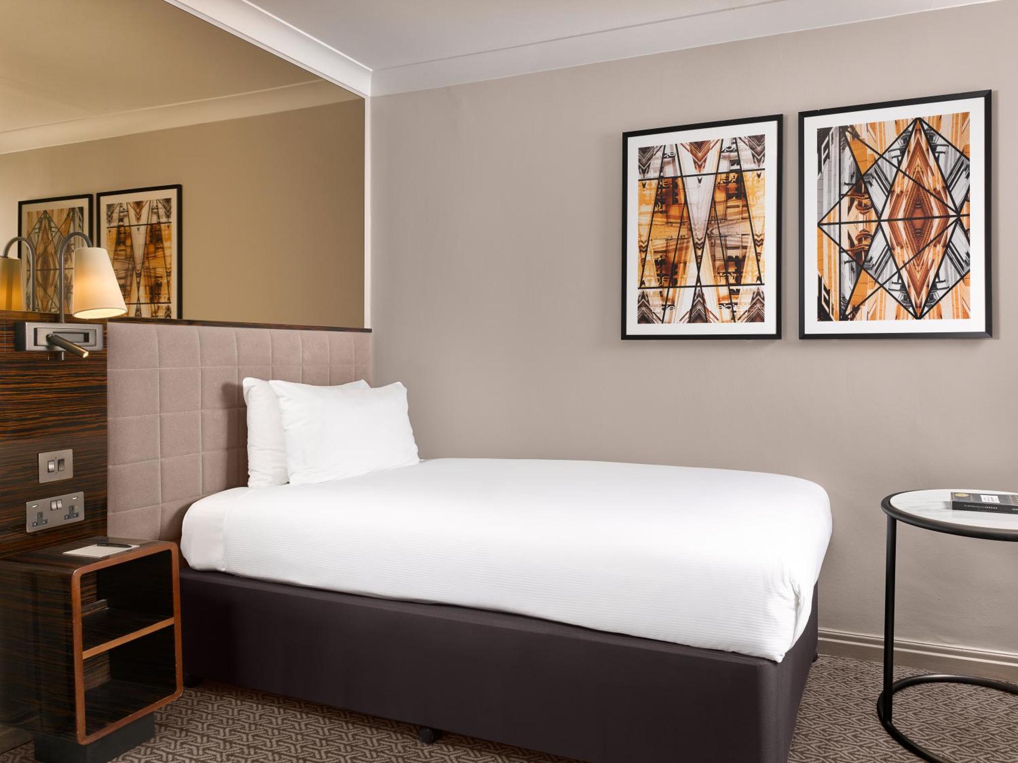 a hotel room with a bed and a table at Strand Palace in London
