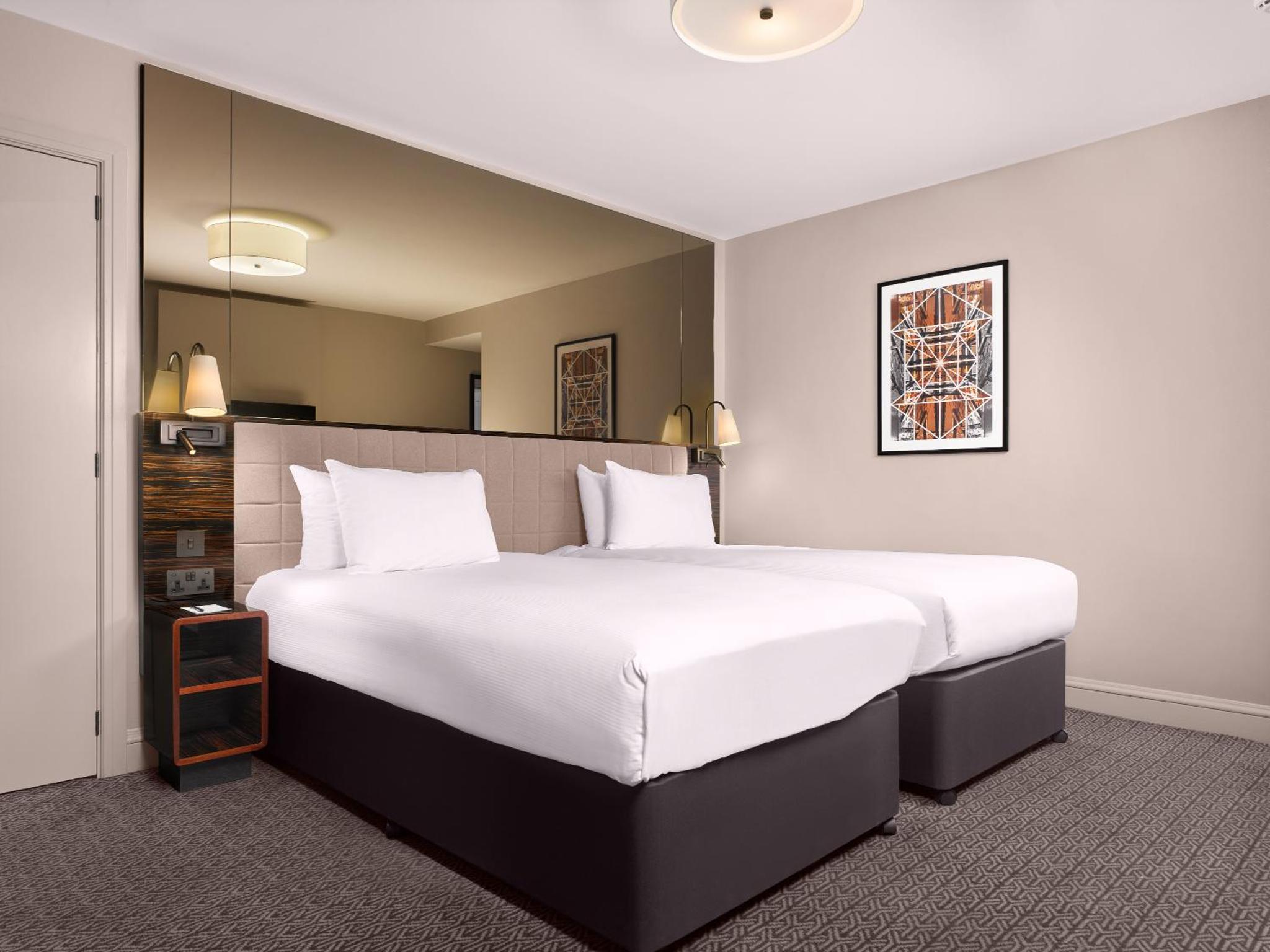 a bedroom with a large bed with white sheets at Strand Palace in London