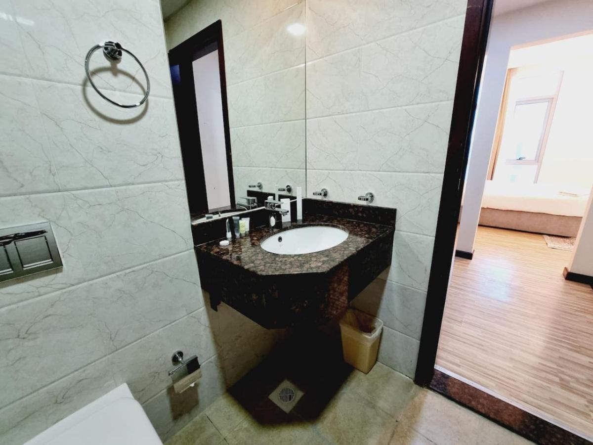 a bathroom with a sink and a large mirror at Aspire Tower-Juffair Modern Comfort Suite in Manama