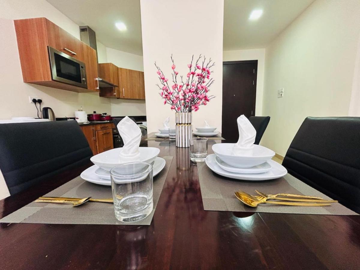 a dining room table with plates and glasses and flowers on it at Aspire Tower-One Bedroom Blissful Nest in Manama