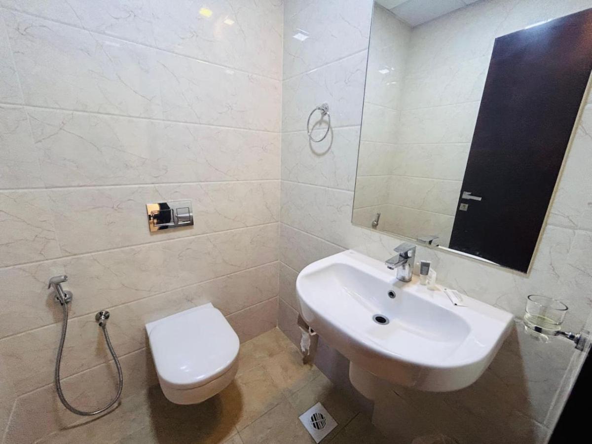 a bathroom with a sink and a toilet and a mirror at Aspire Tower-One Bedroom Sunny Solo Stay in Manama
