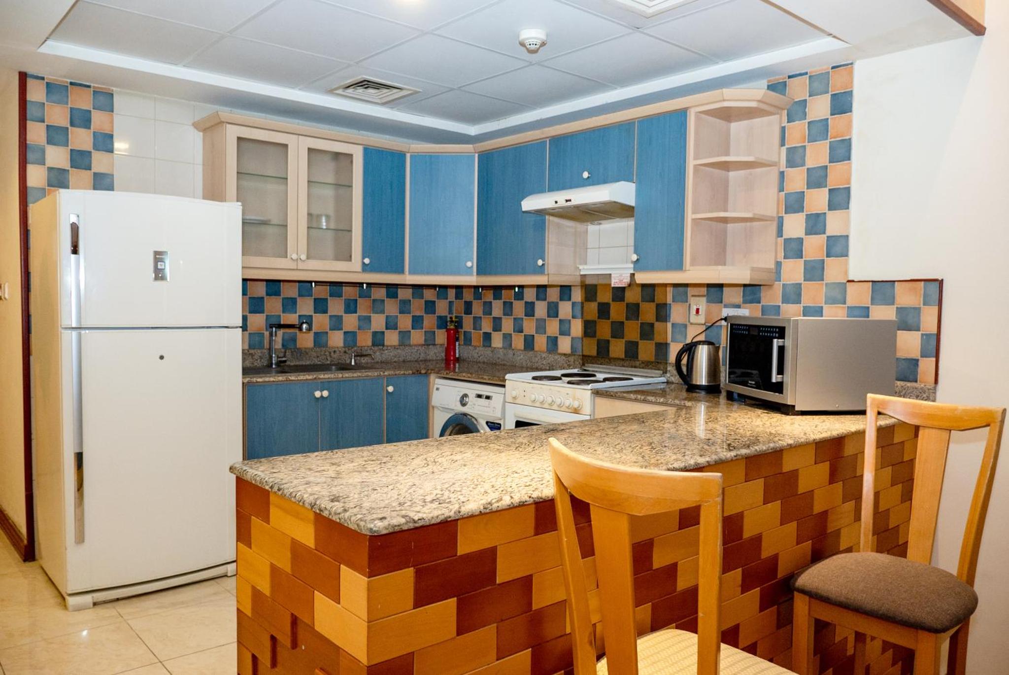 a kitchen with blue cabinets and a white refrigerator at Excelsior Luxury Apartments in Manama