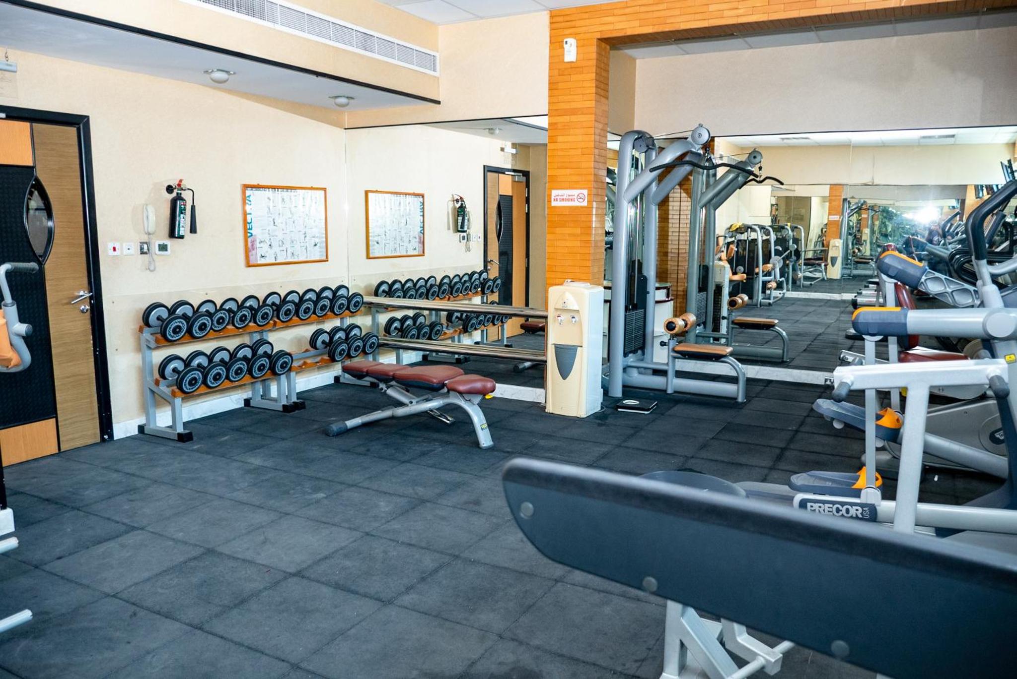 a gym with treadmills and machines in a room at Excelsior Luxury Apartments in Manama