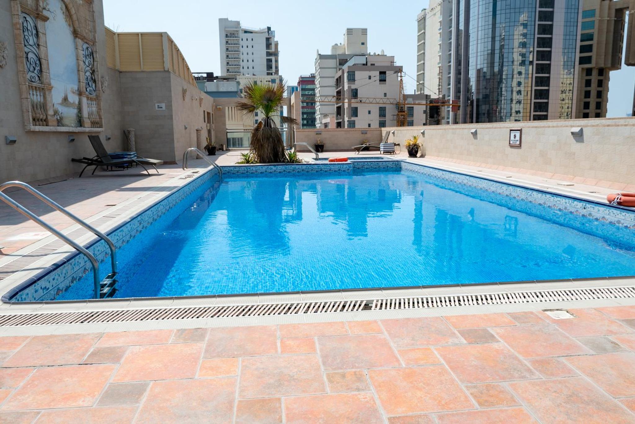 a large blue swimming pool on top of a building at Excelsior Luxury Apartments in Manama