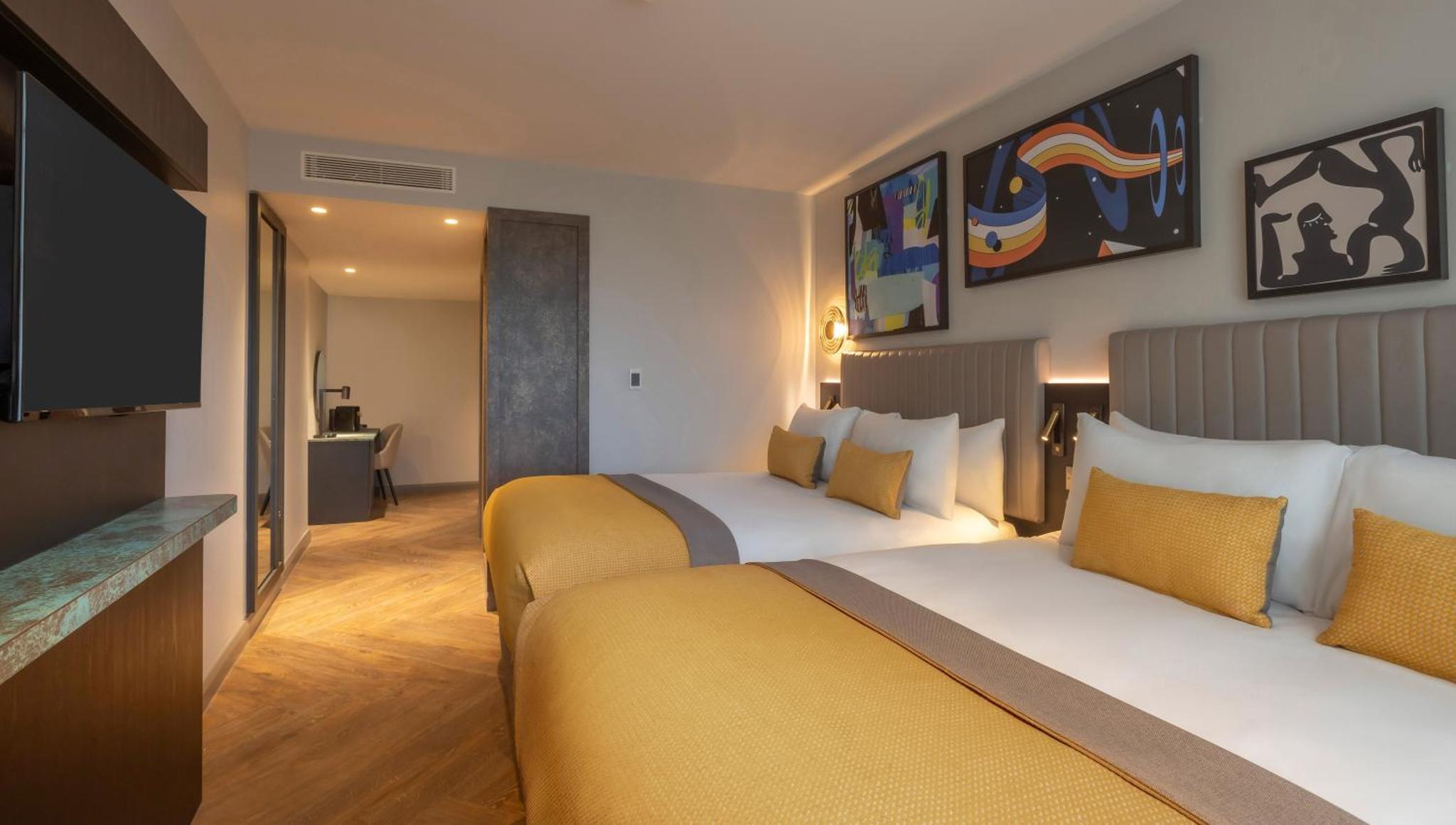 a hotel room with two beds and a flat screen tv at Maldron Hotel Shoreditch London in London