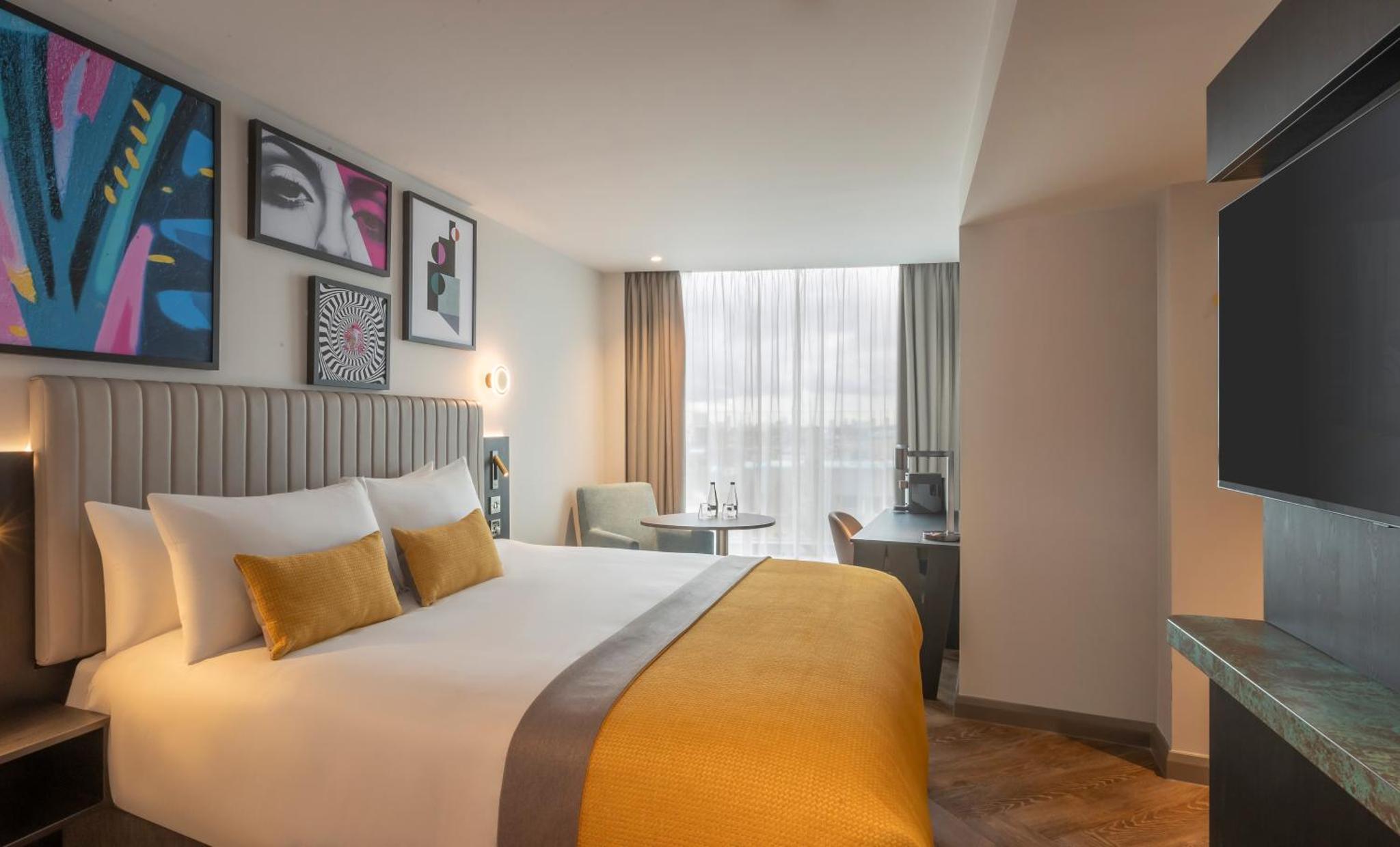 a hotel room with a bed and a flat screen tv at Maldron Hotel Shoreditch London in London +17 photos