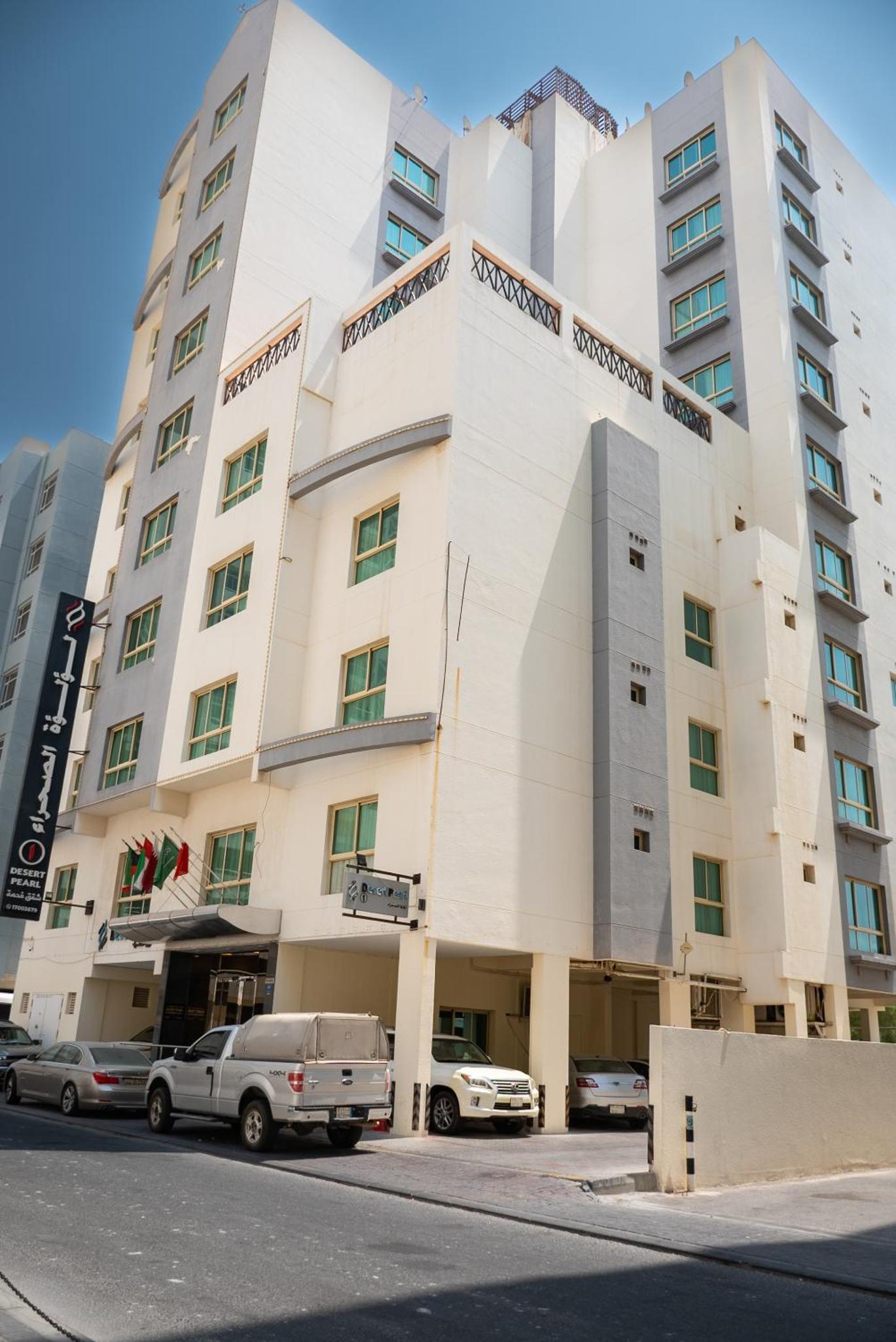 a white building with cars parked in front of it at Desert Pearl Hotel Apartment in Manama
