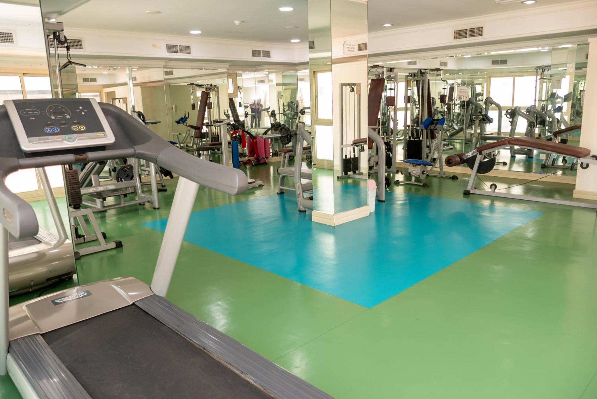 a gym with a blue floor and a treadmill at Desert Pearl Hotel Apartment in Manama