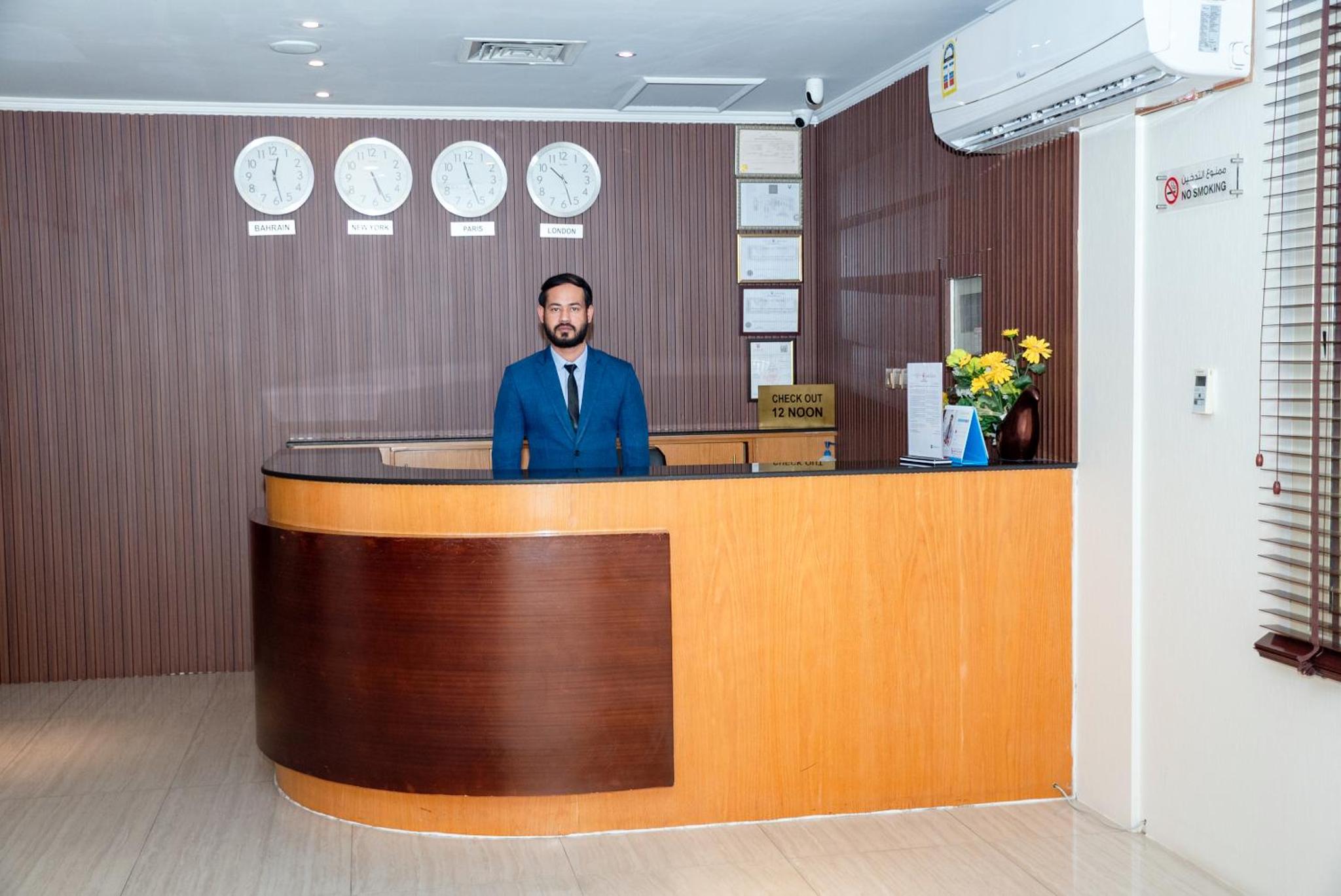 a man in a suit standing at a reception desk at Desert Pearl Hotel Apartment in Manama +28 photos