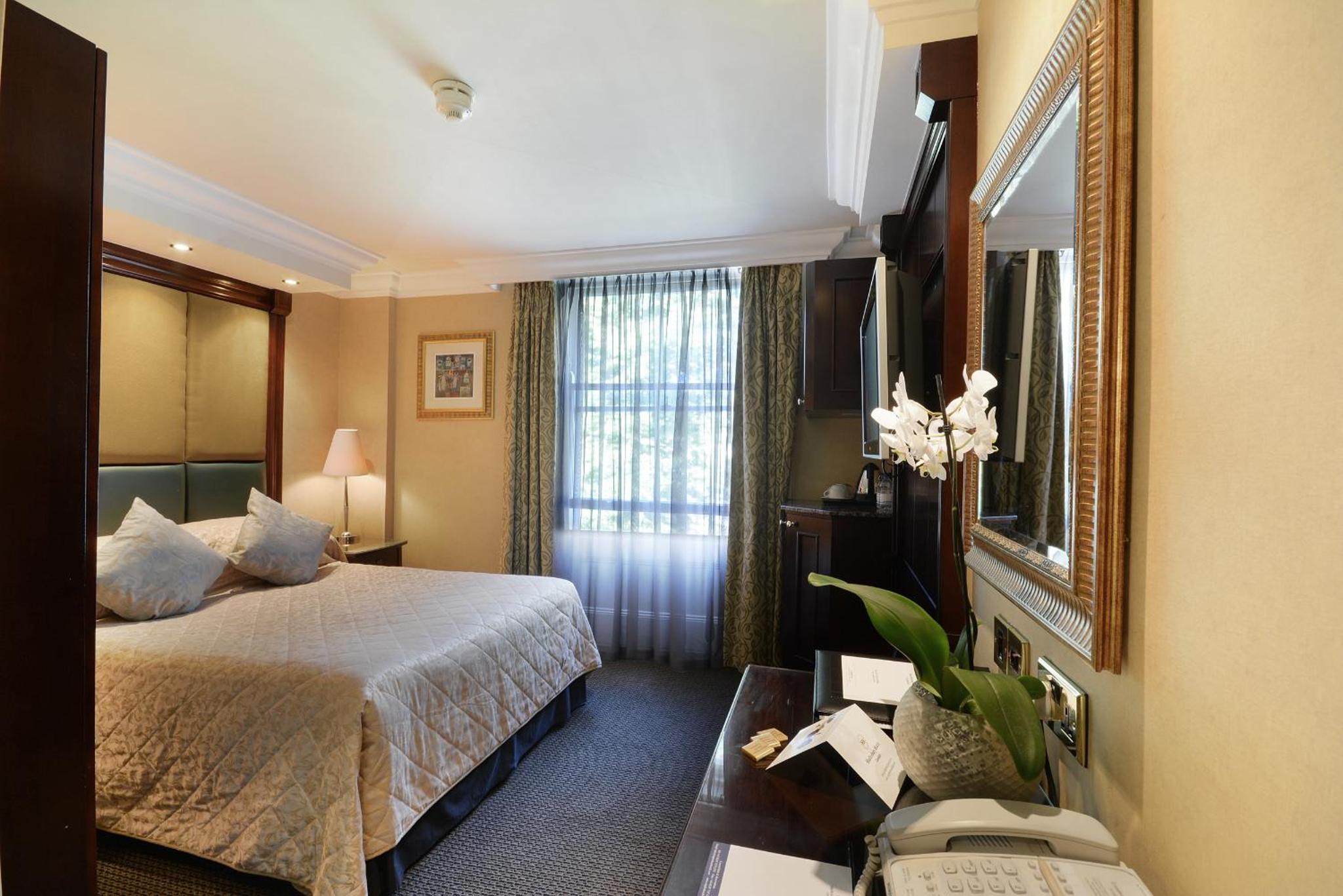 a hotel room with a bed and a mirror at The Premier Notting Hill in London