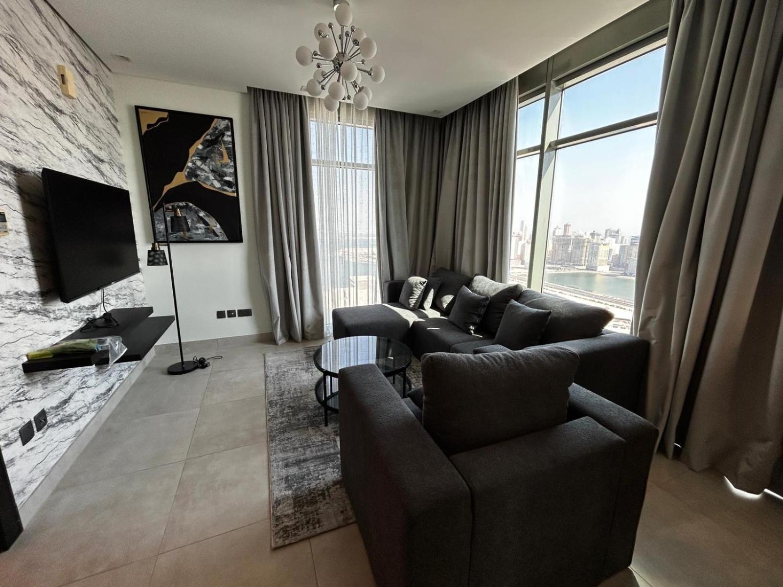 a living room with a couch and a tv at Holiday Homes- Apartment in Manama