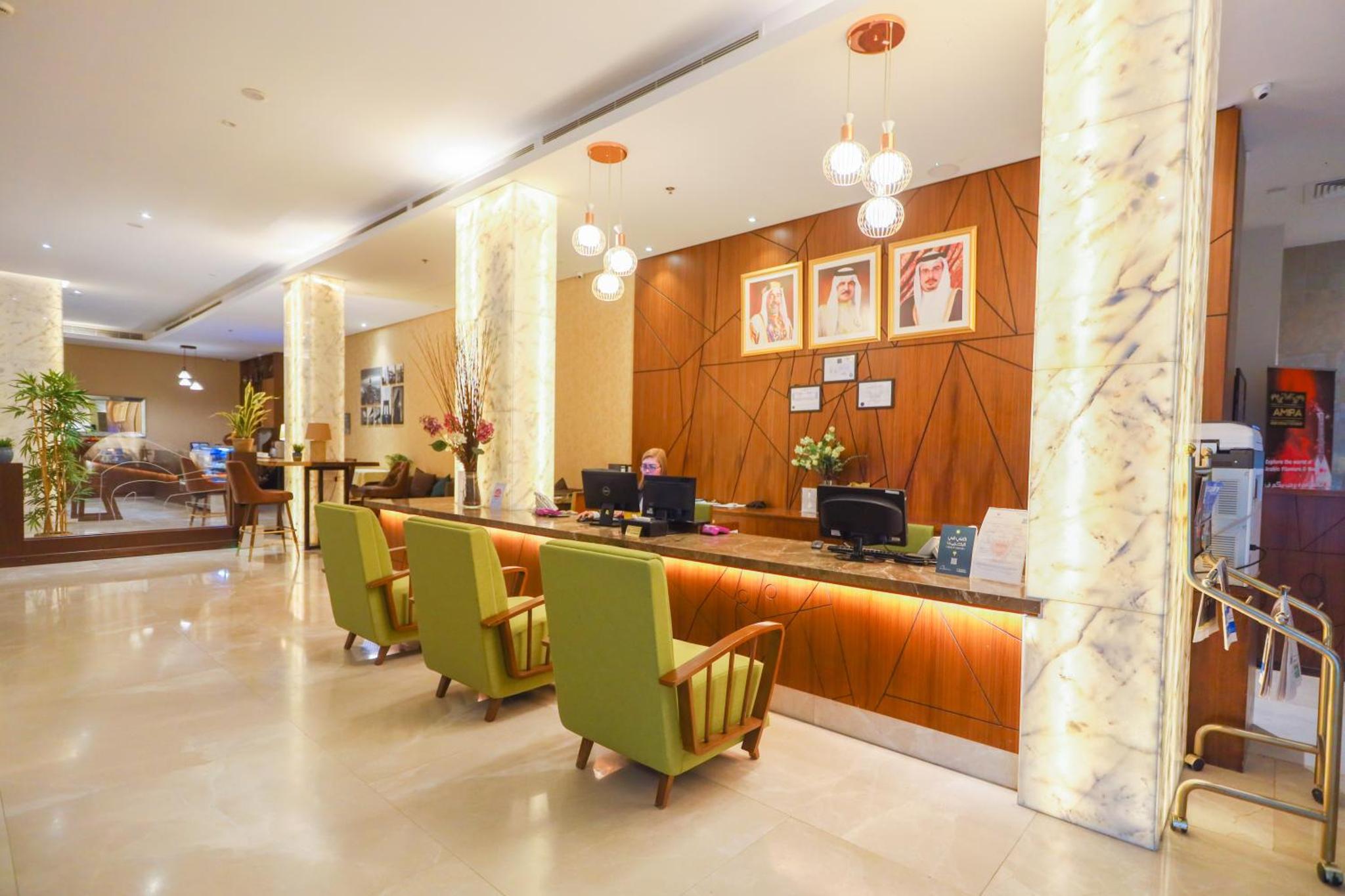 a lobby with a bar with green chairs at Ramee Palace Hotel in Juffair