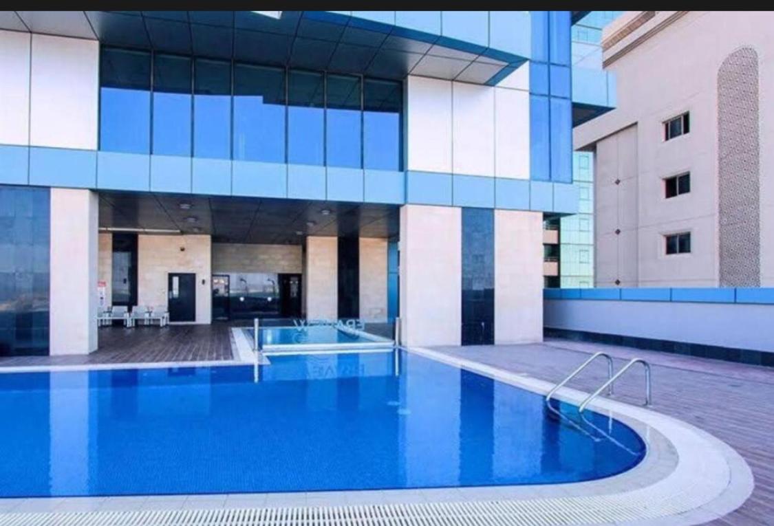 a large building with a large blue swimming pool at Holiday Homes- Apartment in Manama