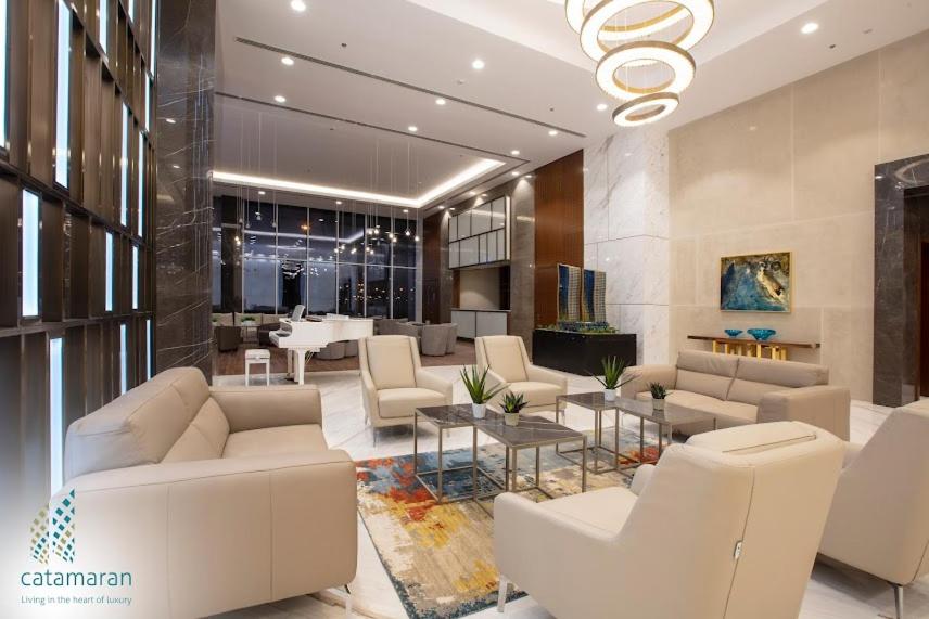 a lobby with white furniture and a chandelier at Cozy Stay in Manama