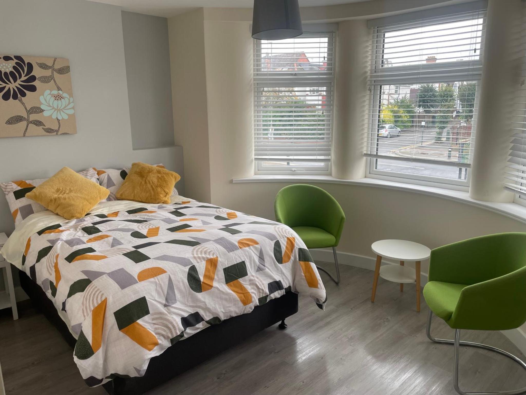 a bedroom with a bed and two green chairs at Regal Hotel in London