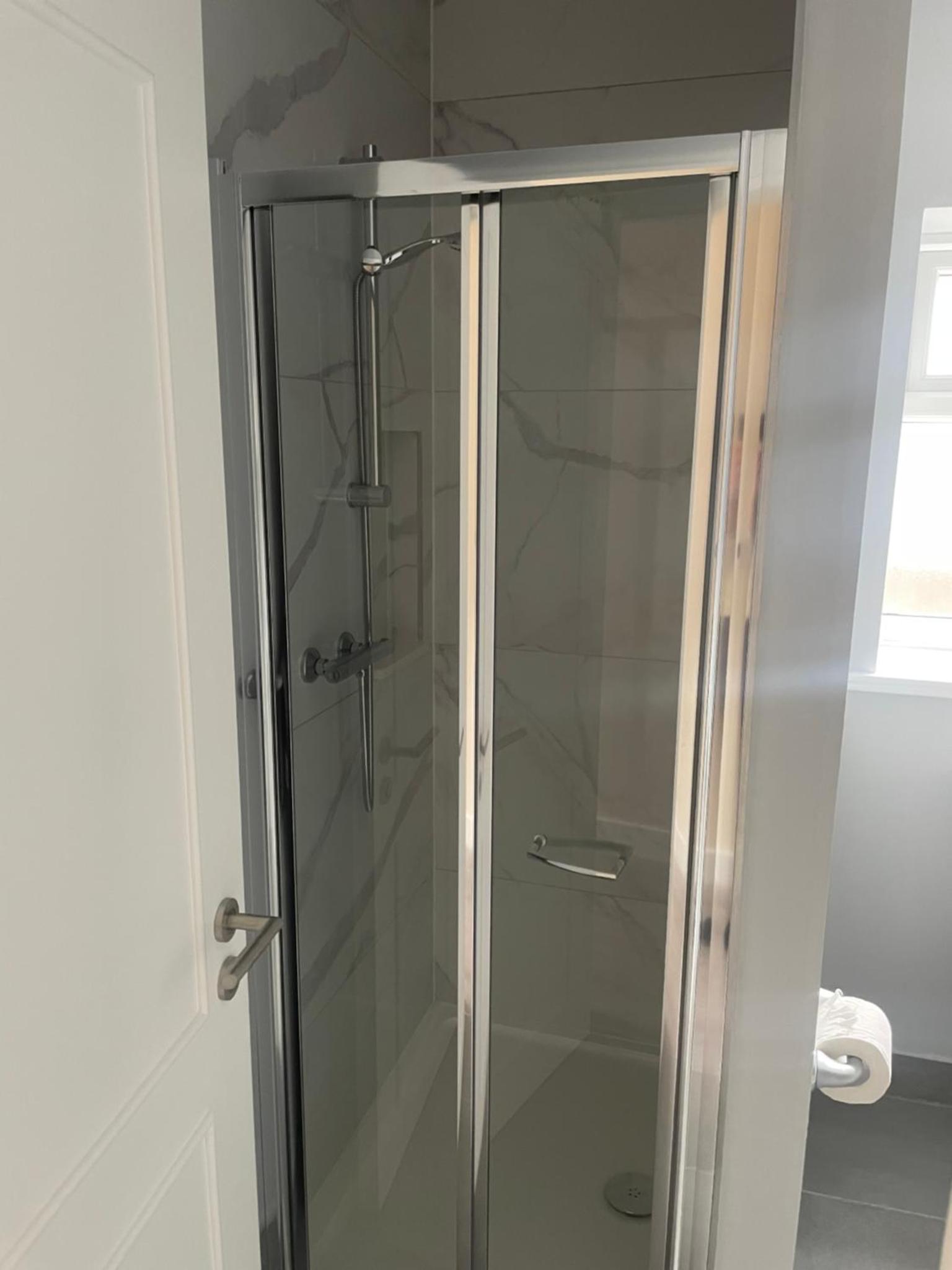 a shower with a glass door in a bathroom at Regal Hotel in London