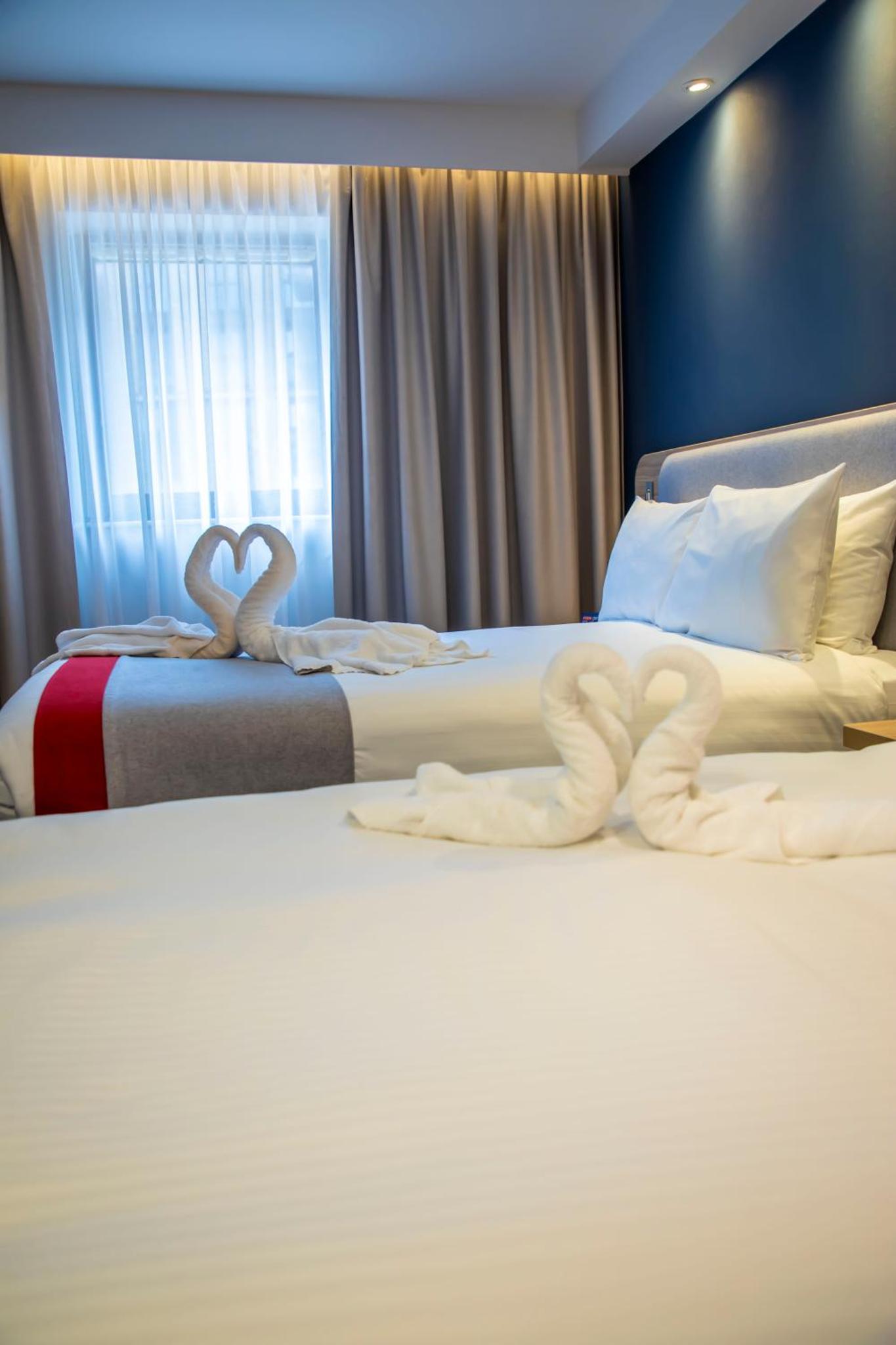 two beds with towel swans in a hotel room at Holiday Inn Express Royal Docks by IHG in London