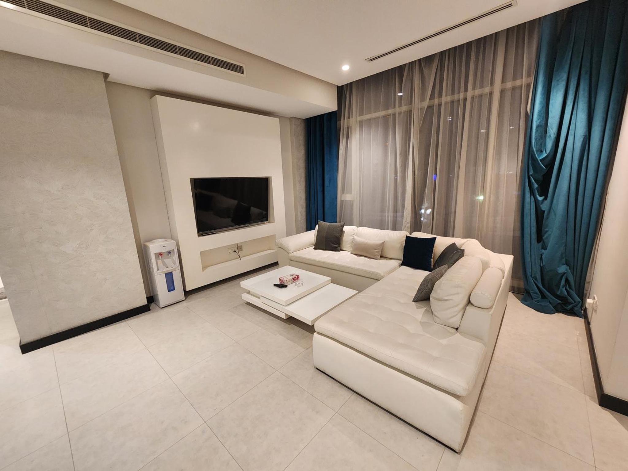a living room with a white couch and a tv at Stunning Sea View 3BR Duplex in Reef Island in Sanābis