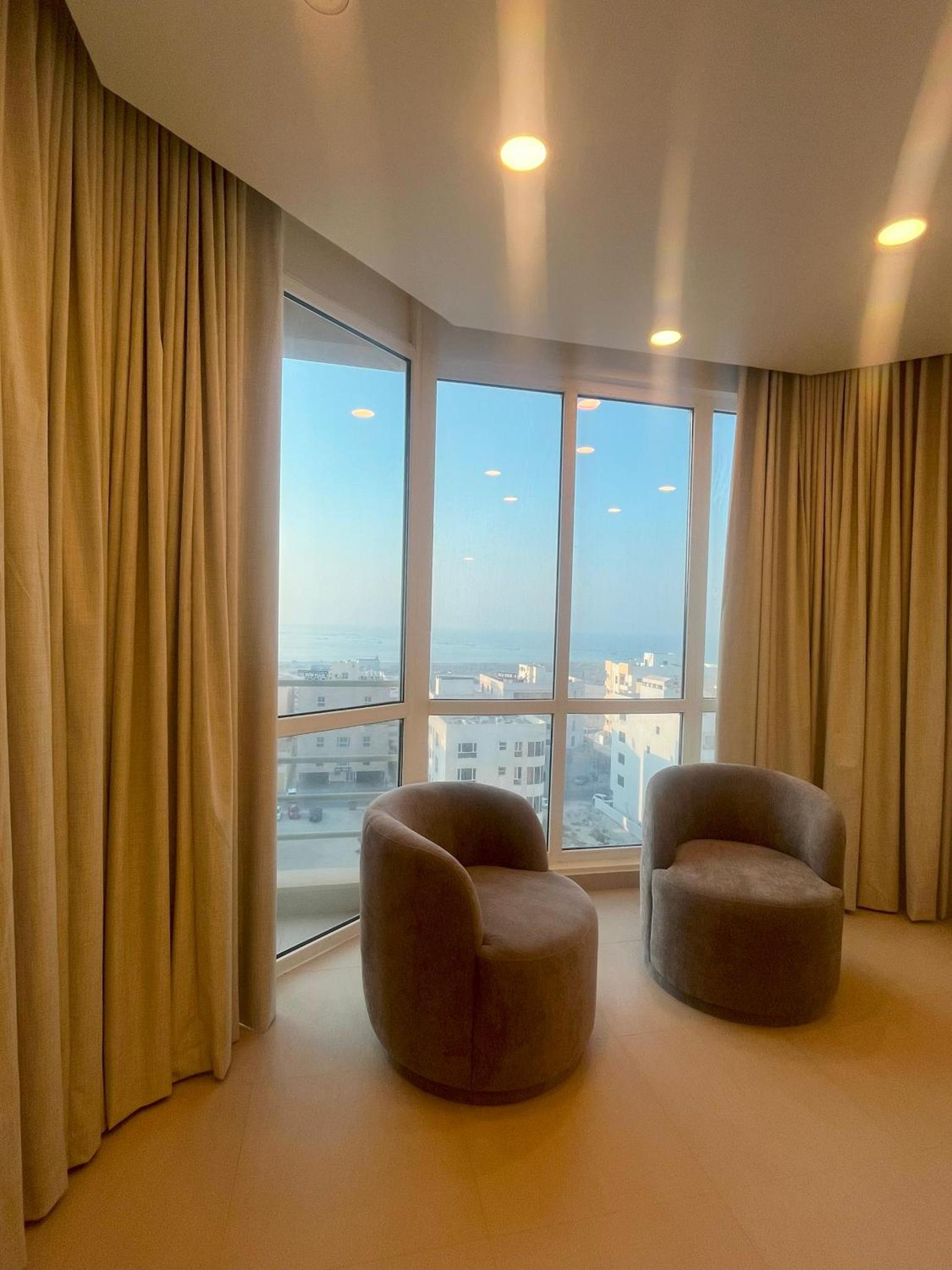 a living room with two chairs and a large window at Talia Residence in Seef