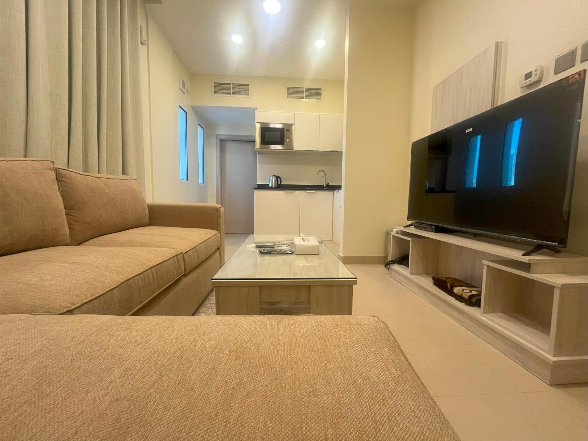 a living room with a couch and a large flat screen tv at Talia Residence in Seef
