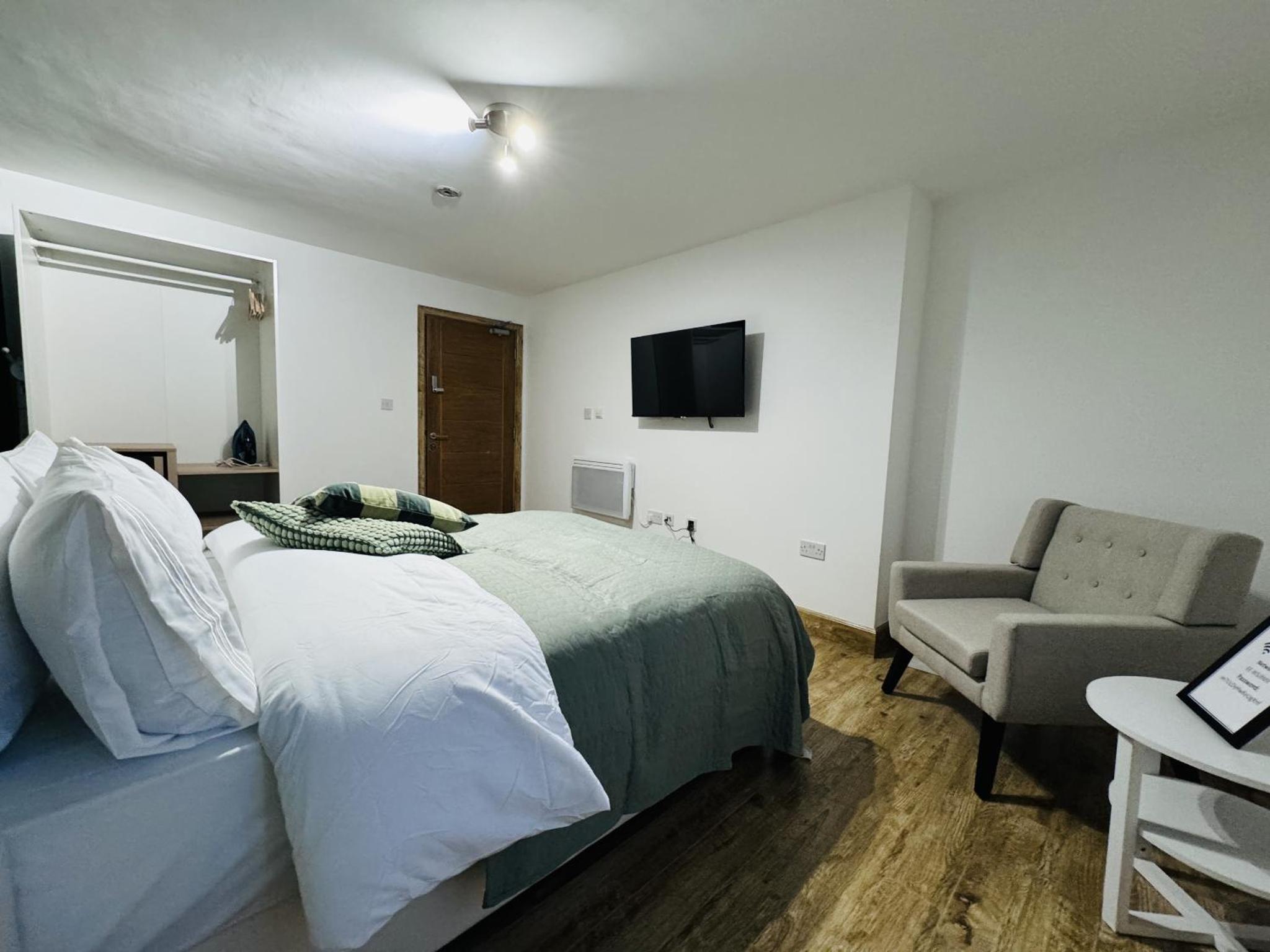 a bedroom with a bed and a chair and a television at The Edge FT3 in London