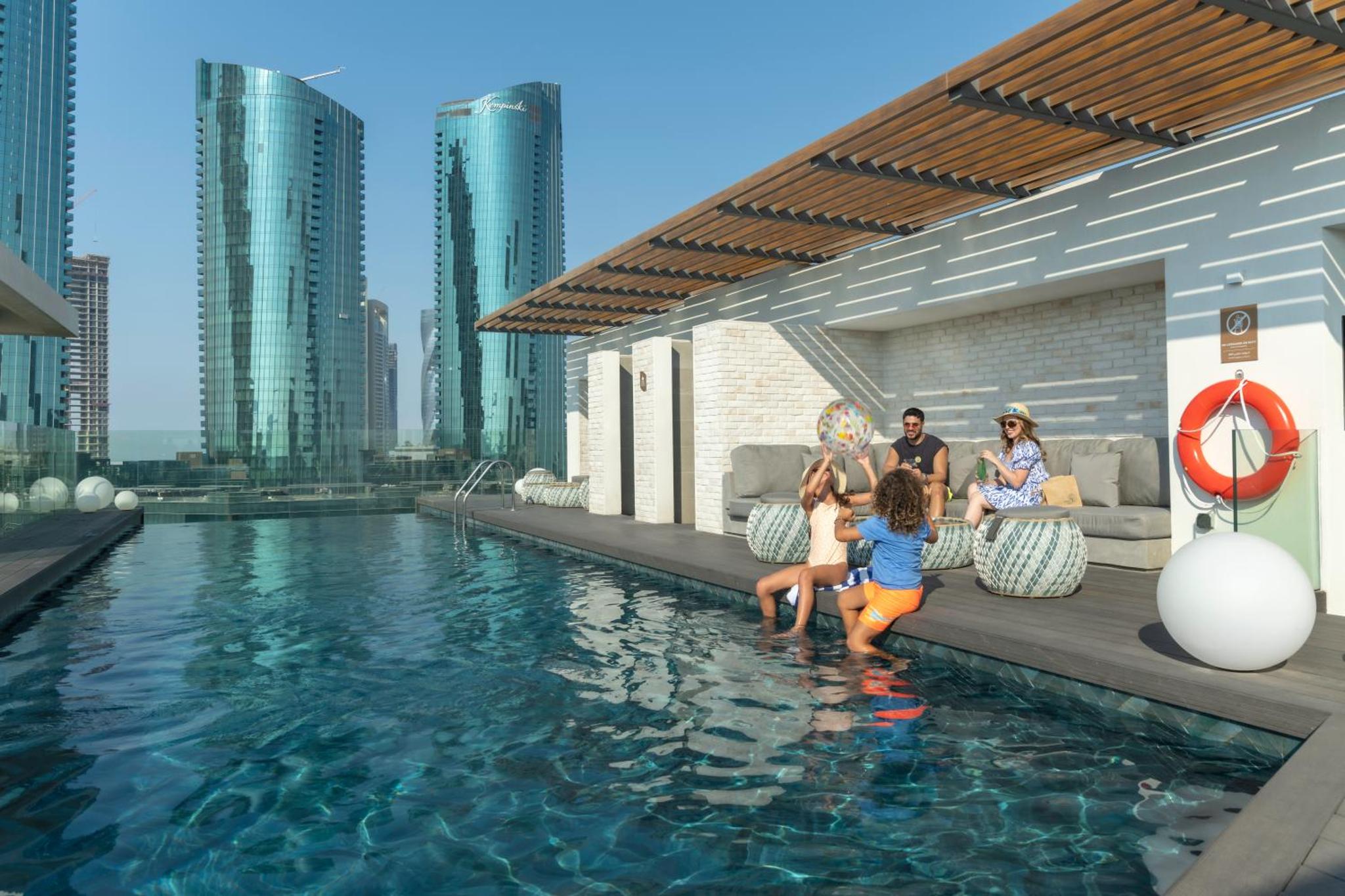 a group of people sitting next to a swimming pool at Pearlhouse Bahrain in Manama