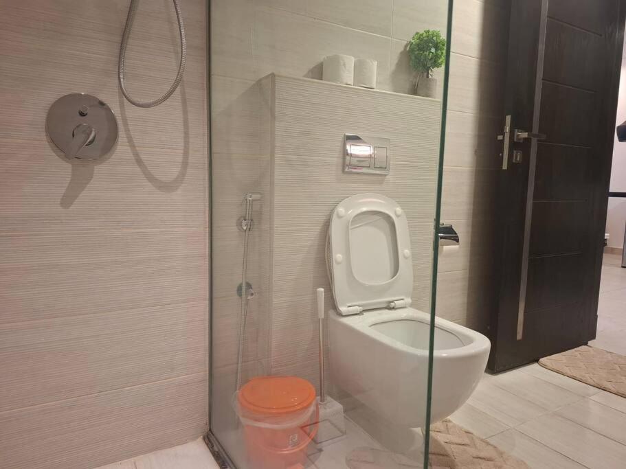 a bathroom with a toilet and a glass shower at Home on Holiday -Apartments in Manama