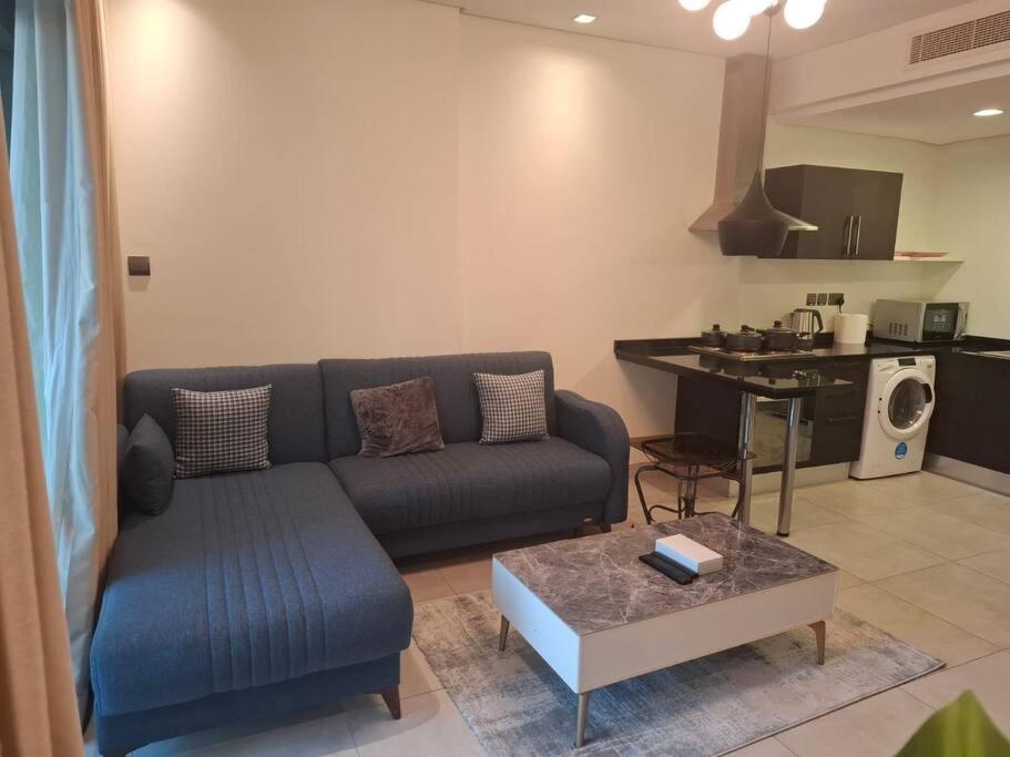 a living room with a blue couch and a table at Home on Holiday -Apartments in Manama